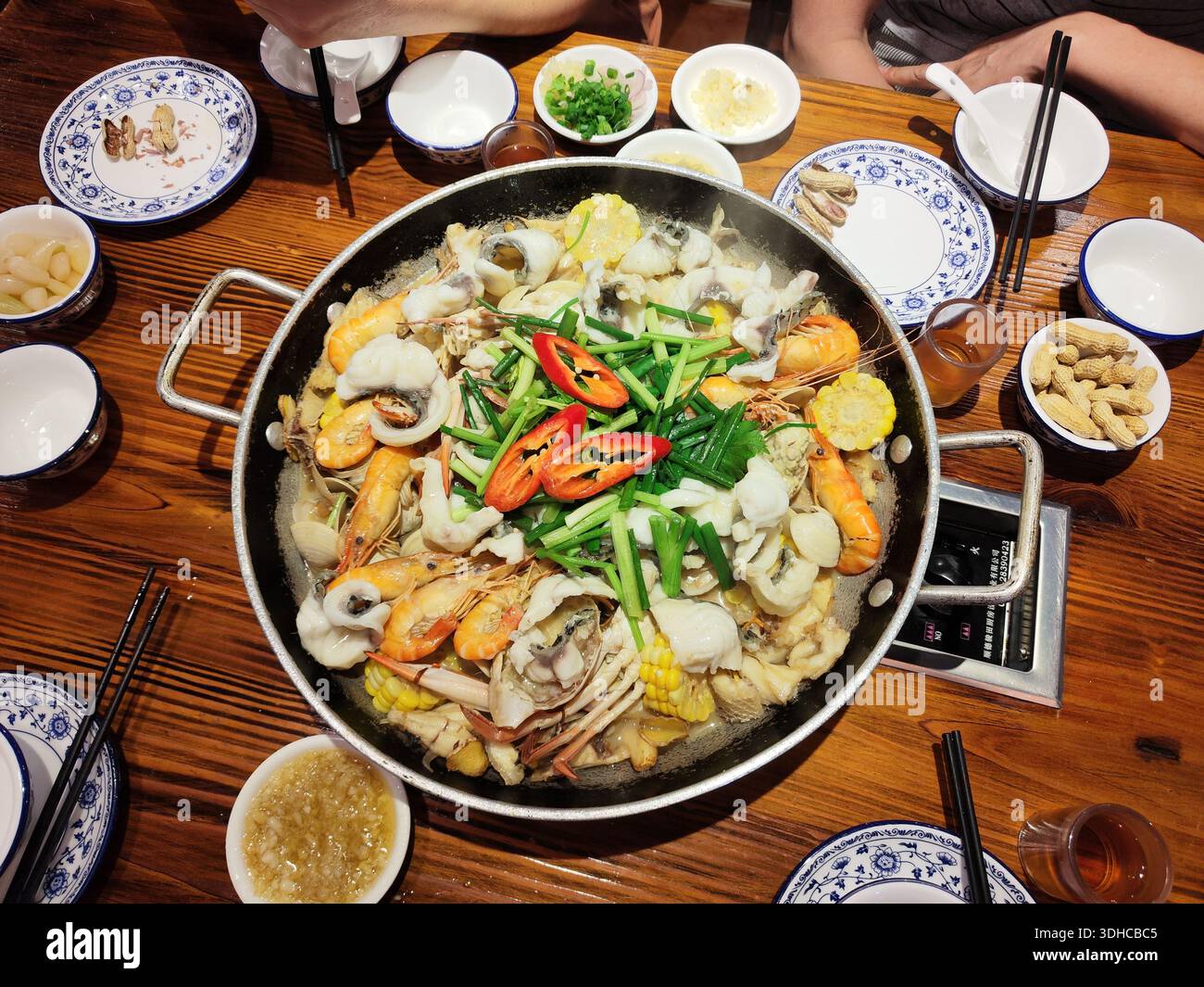 Cuisson à la vapeur d'un hot pot de fruits de mer avec légumes et accompagnements sur une table en bois Banque D'Images