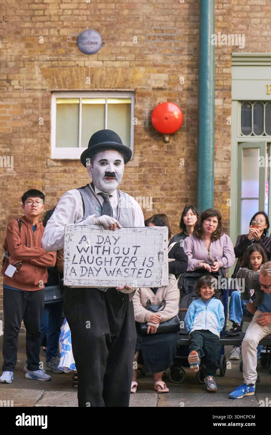 Royaume-Uni, Londres, Covent Garden Market, Un artiste de rue habillé en Charlie Chaplin, connu sous le nom de Charlot, présente une citation de l'acteur anglais et pionnier du cinéma muet : une journée sans rire est une journée perdue Banque D'Images