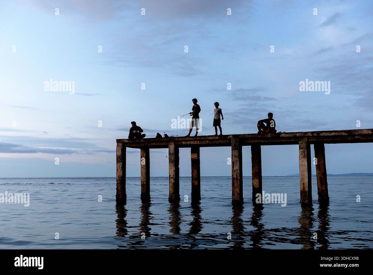 Enfants pêchant sur un vieux quai de pêche près de manado dans la partie nord de sulawesi, indonésie Banque D'Images