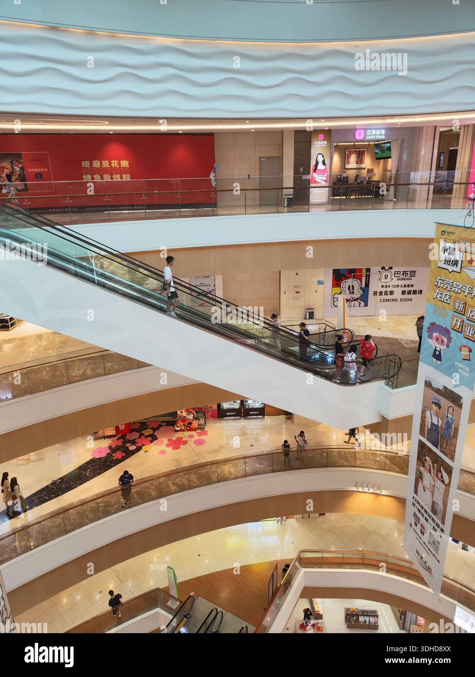 Vue intérieure d'un centre commercial moderne à plusieurs niveaux avec escaliers roulants et magasins Banque D'Images