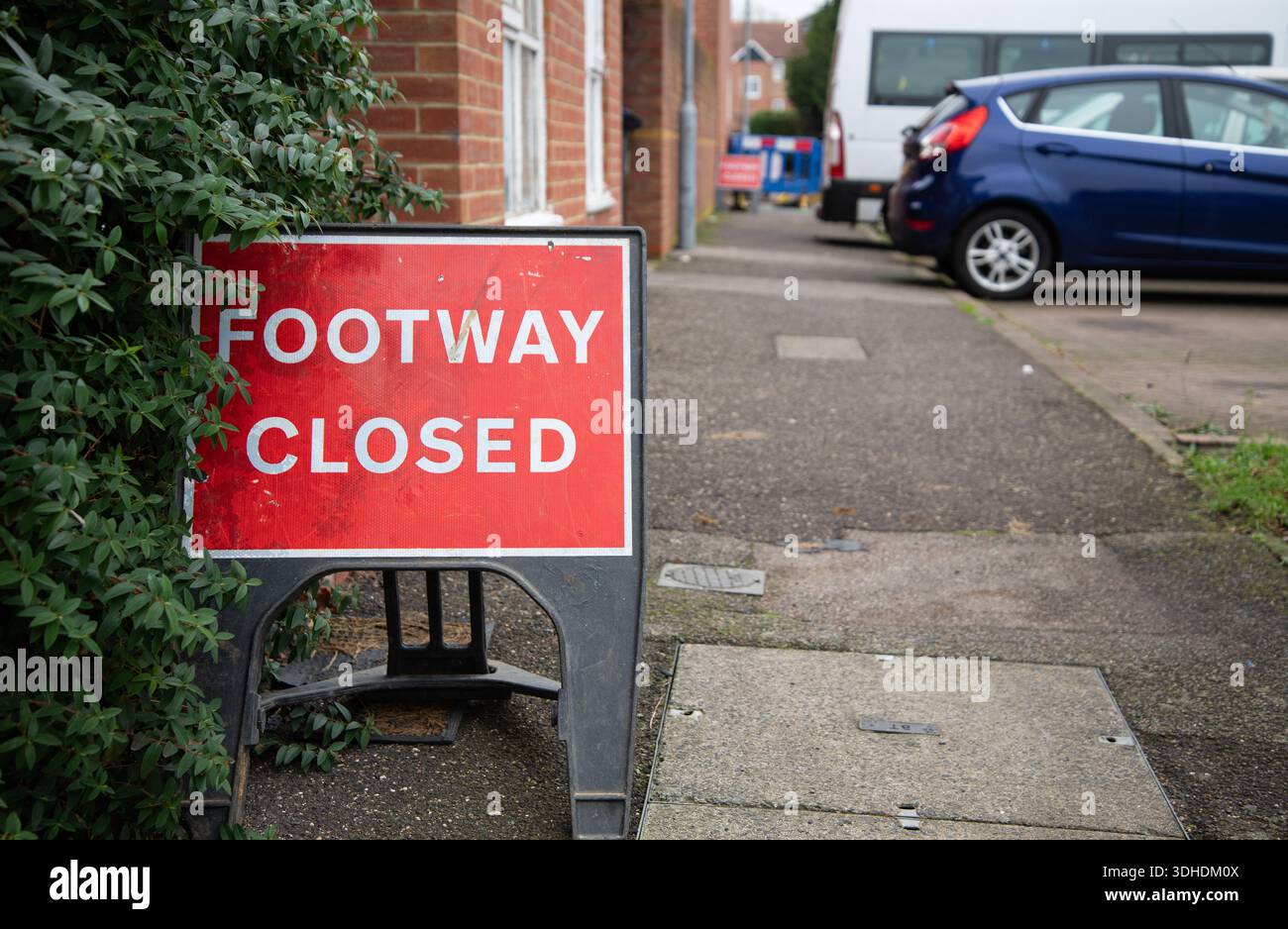 Gros plan d’un panneau rouge « Footway Closed » sur un trottoir, signalant des restrictions piétonnes temporaires ou des travaux de construction. Banque D'Images
