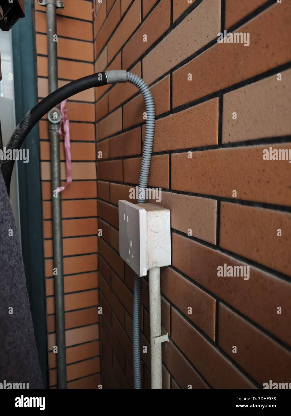 Conduit électrique et boîte de jonction montés sur un mur de briques Banque D'Images