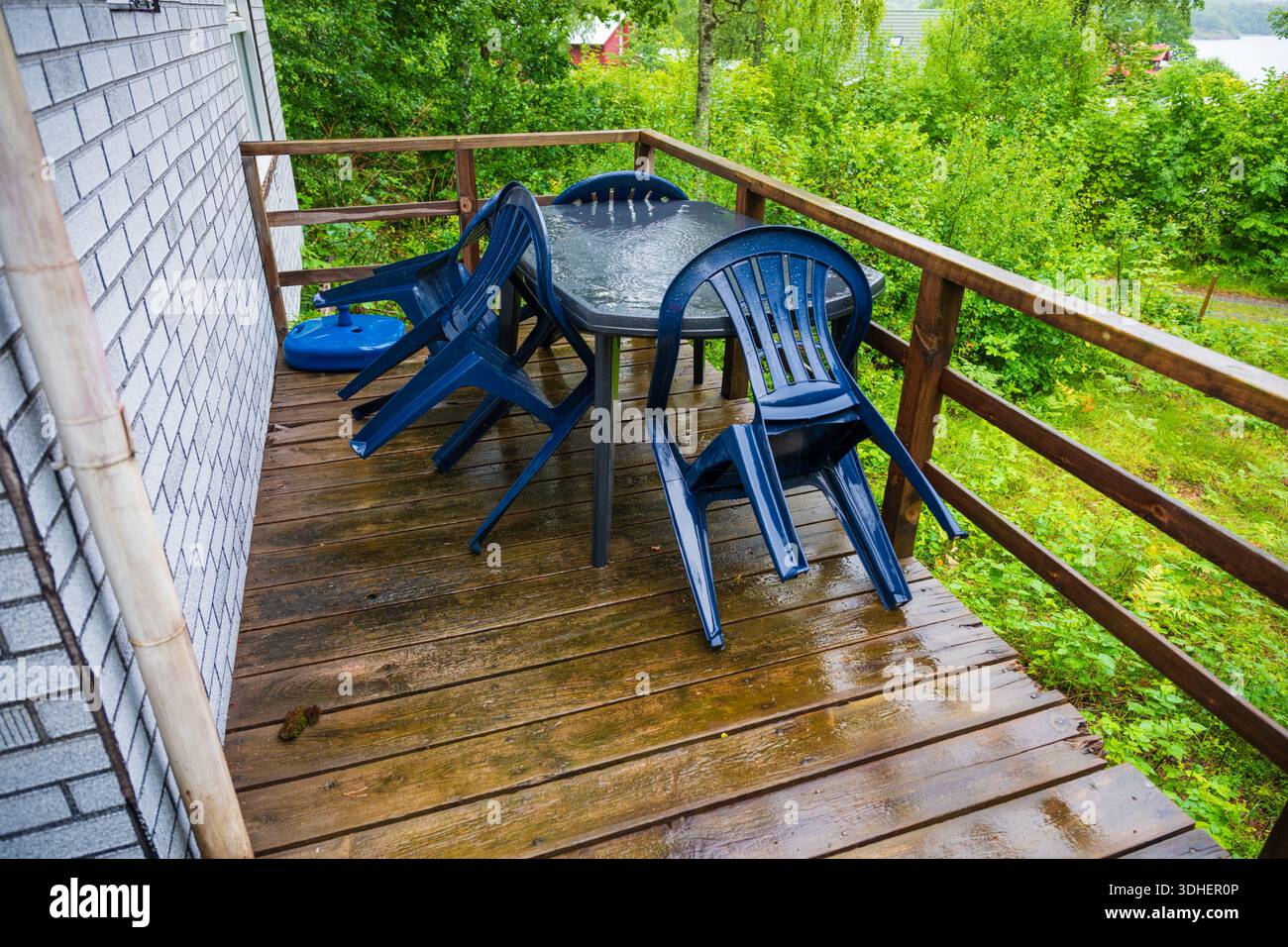 Patio baigné de pluie avec chaises empilées en plastique Banque D'Images