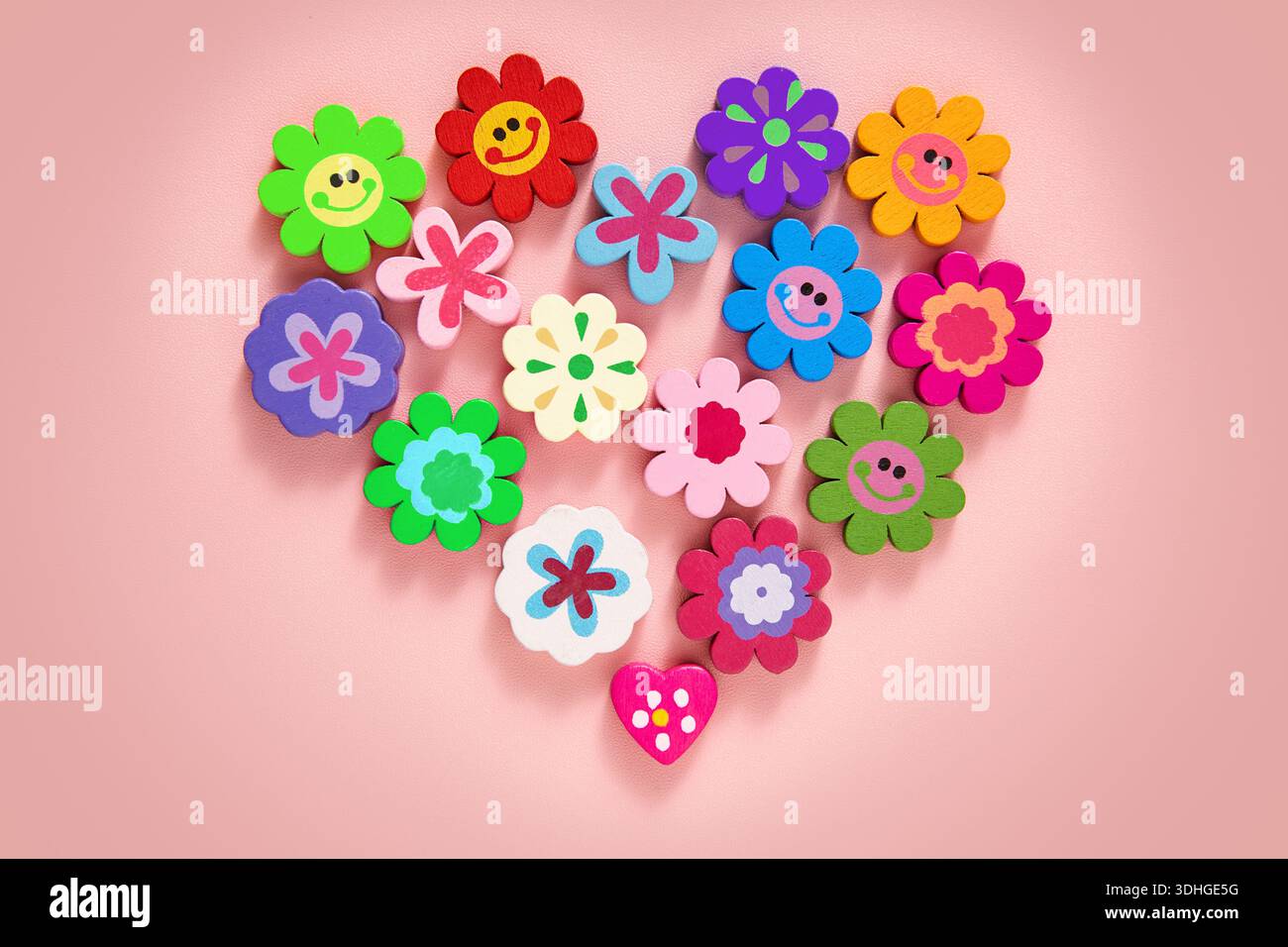 Un motif à plat en forme de coeur vibrant avec une collection de décorations colorées en forme de fleurs, de visages souriants et en forme de coeur Banque D'Images