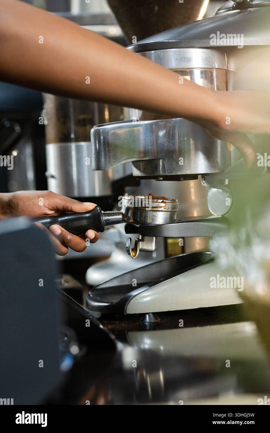 Porte-filtre espresso se verrouillant dans la tête du groupe sur le comptoir réfléchissant du café, reflets métalliques chauds Banque D'Images