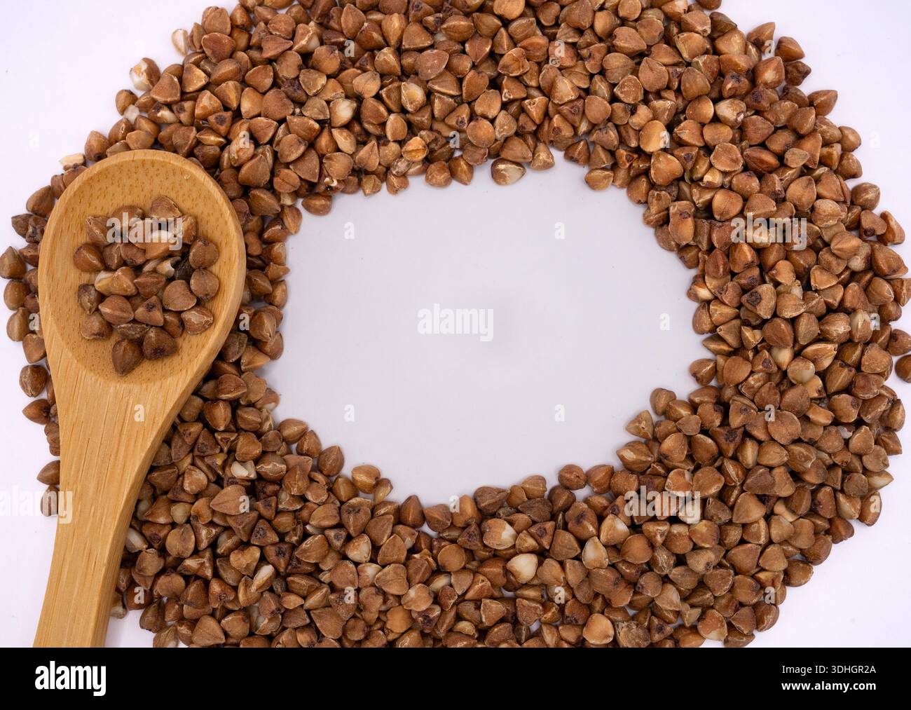 Composition créative de gruaux de sarrasin disposés dans un cadre circulaire avec une cuillère en bois. Fond de nourriture saine avec espace de copie. Banque D'Images