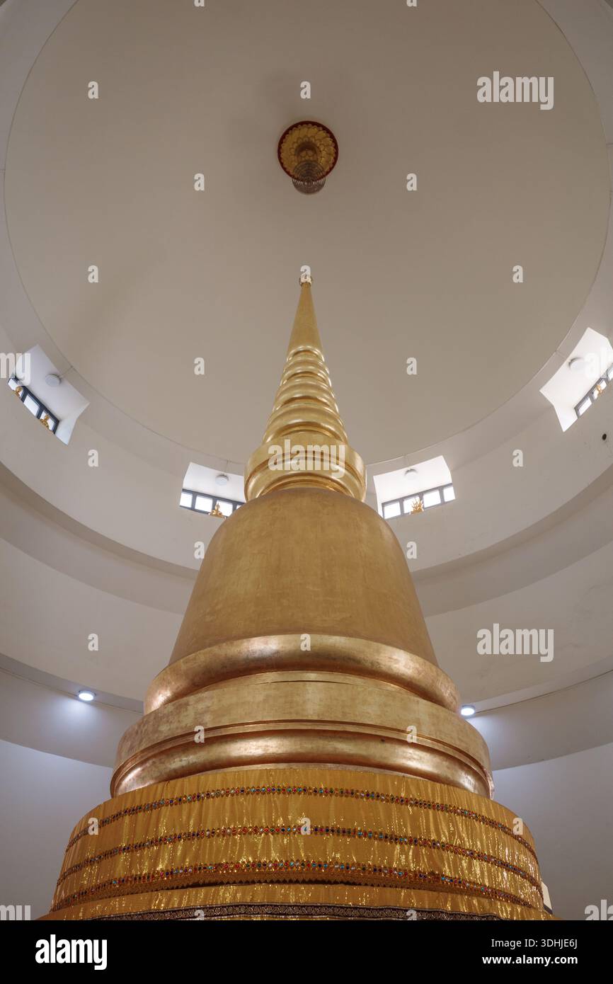 Plan intérieur à angle bas d'un stupa bouddhiste ou pagode de couleur or situé sous un dôme circulaire blanc et propre avec de petites fenêtres. Banque D'Images