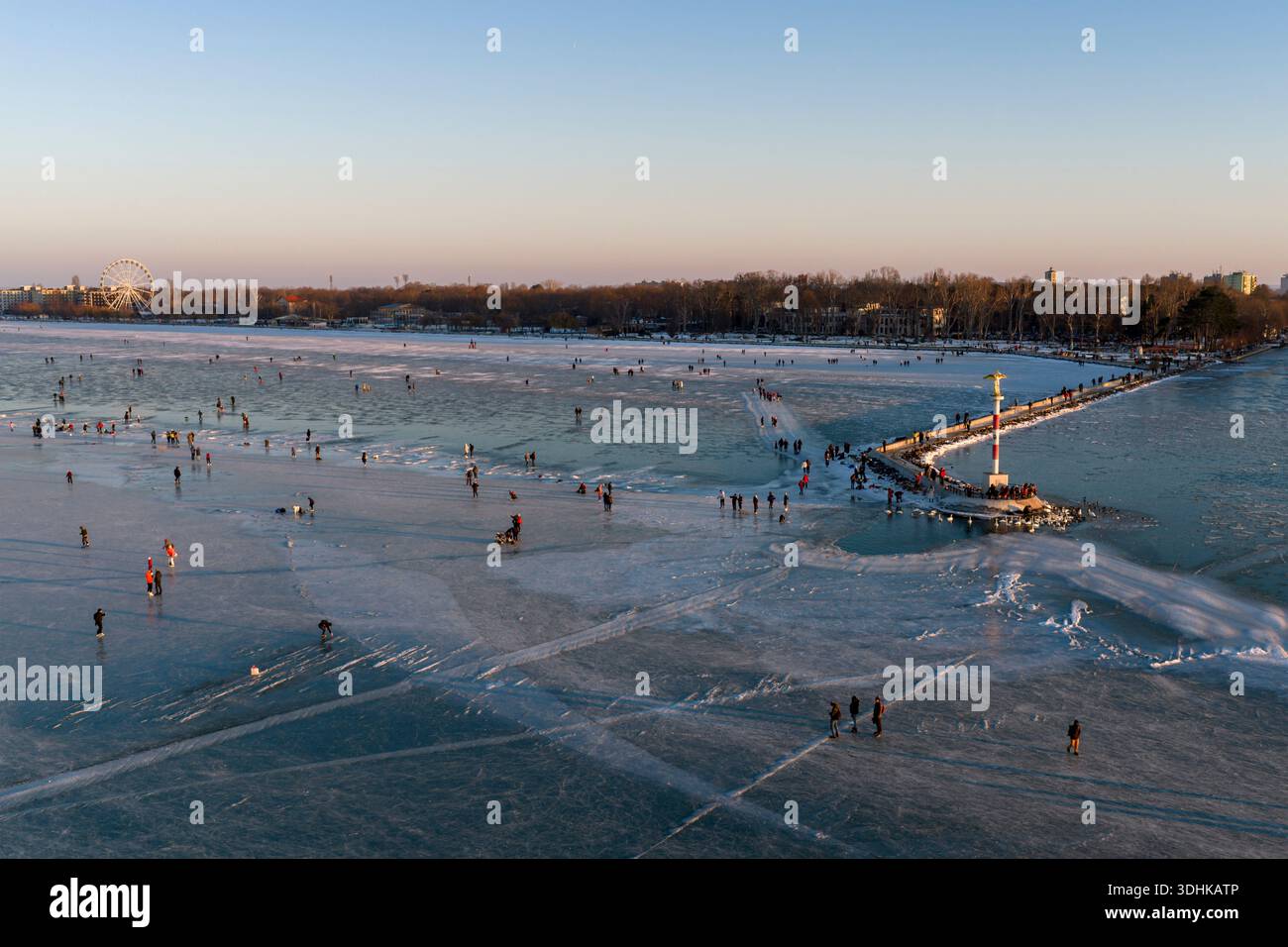 Des gens heureux patinant dans le lac gelé Balaton à la plage de la ville de Siofok en Hongrie. Banque D'Images