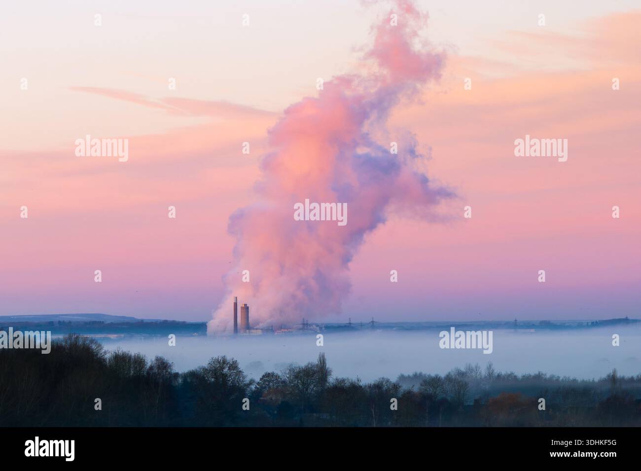 Vue aérienne de l'usine industrielle enveloppée dans la brume matinale, ses cheminées s'élevant contre les douces teintes roses et bleues du ciel de l'aube, Wittenha Banque D'Images