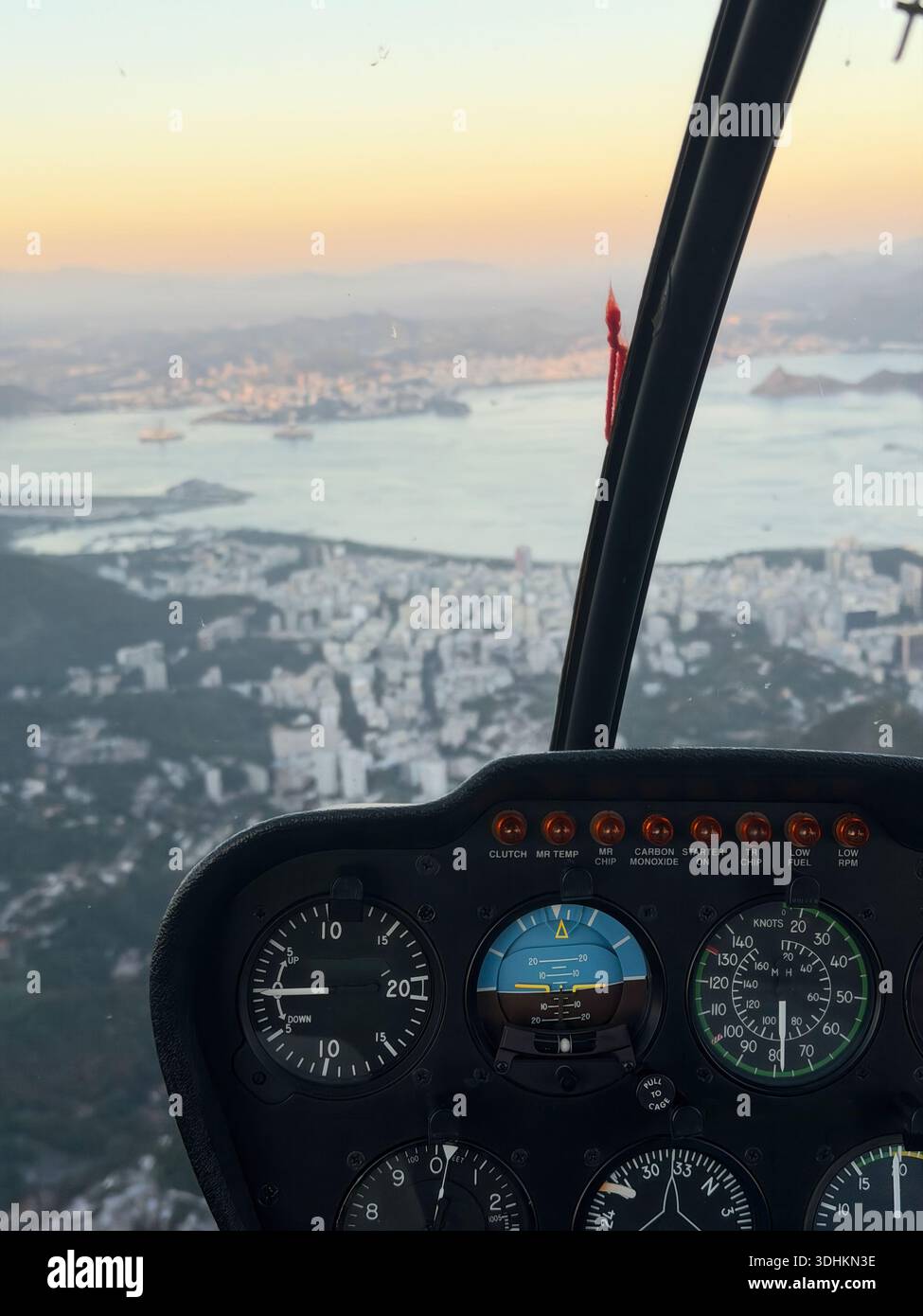 Groupe d'instruments de cockpit d'hélicoptère avec vue aérienne sur la ville et la baie au coucher du soleil, concept d'aviation de voyage. Banque D'Images
