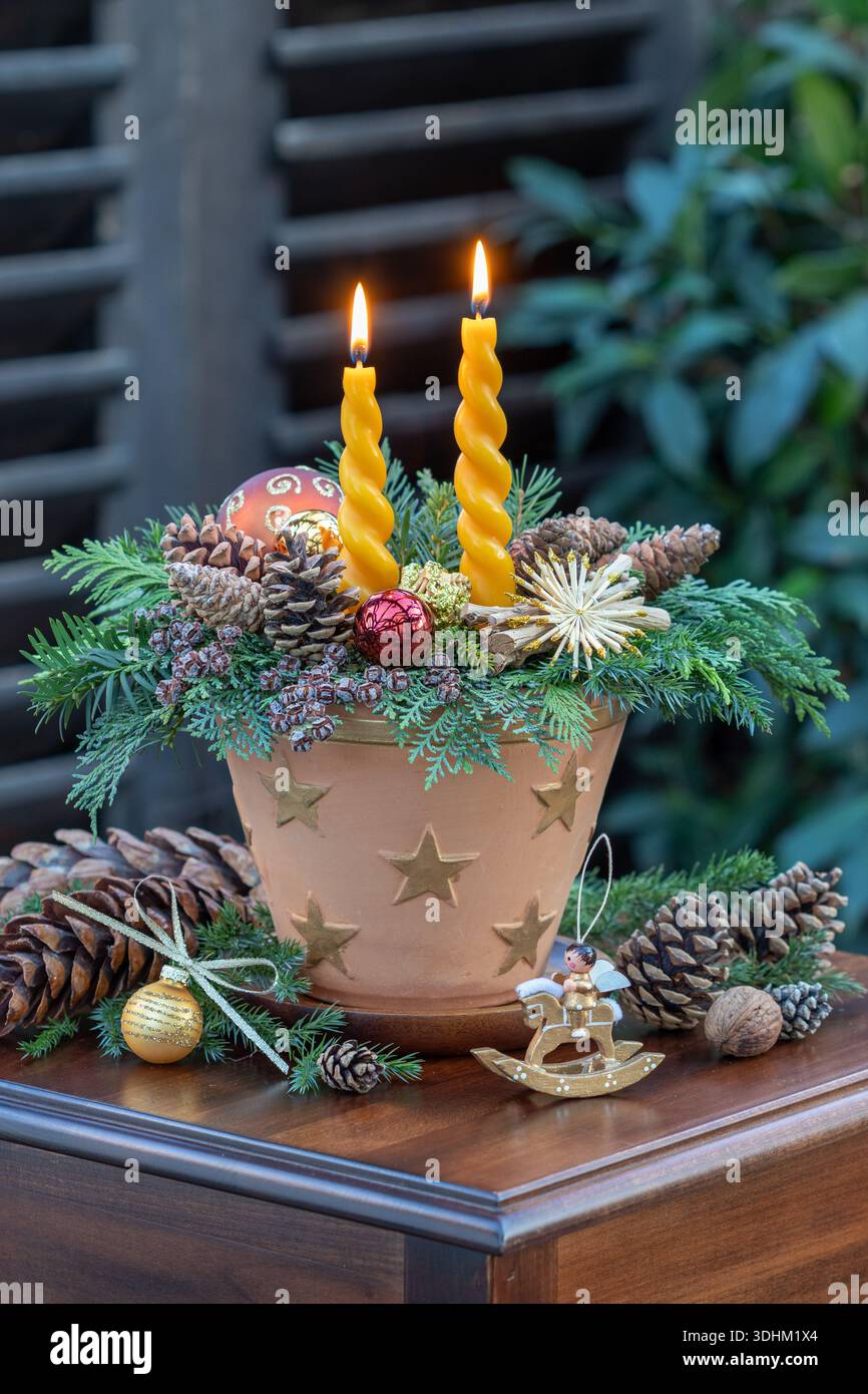 arrangement de noël avec des bougies, des branches de conifères, des boules d'arbre de noël et des cônes dans un pot en terre cuite avec ornement d'étoile Banque D'Images