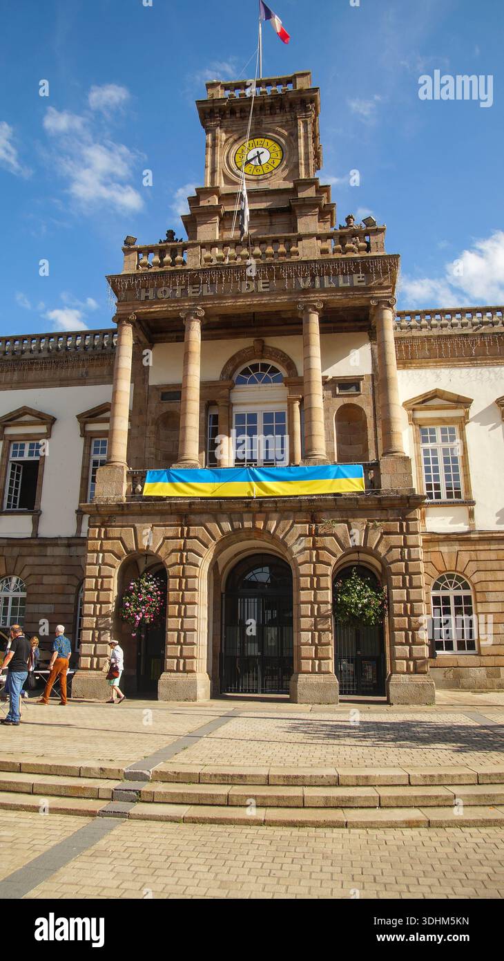 Hôtel de ville orné d'une tour de l'horloge et d'un drapeau ukrainien, avec des gens passant devant la façade historique. Banque D'Images
