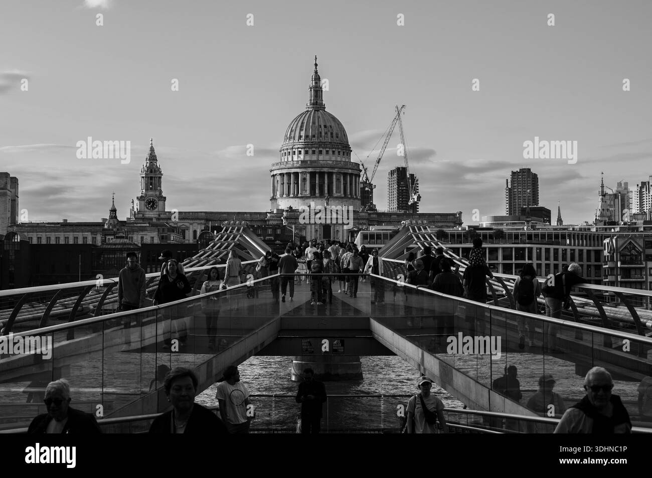 Les piétons traversent le Millennium Bridge à Londres, au Royaume-Uni, avec le dôme de la cathédrale de Paul en arrière-plan. Grues de construction et buil moderne Banque D'Images