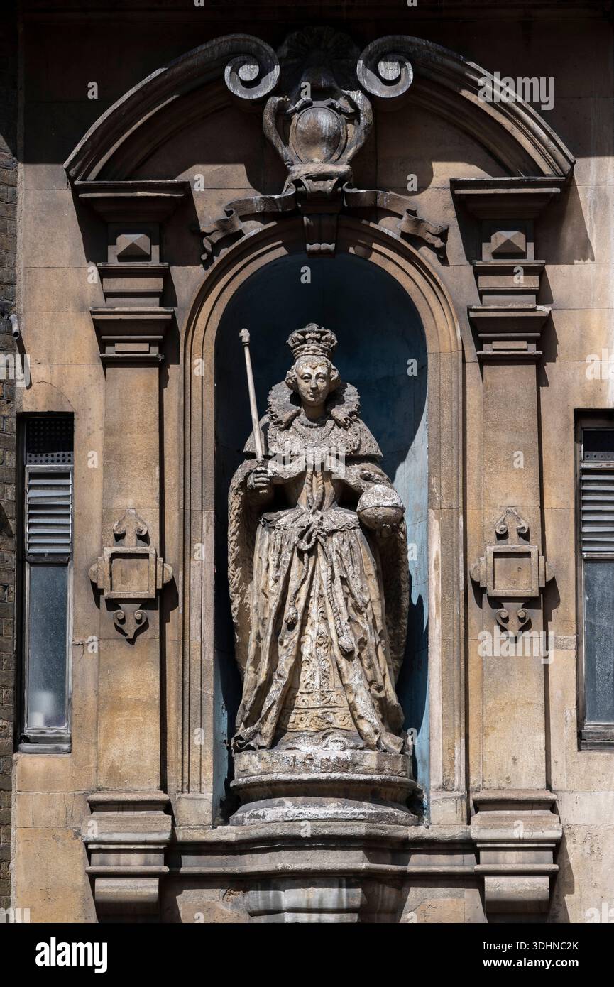 Une statue en pierre de la reine Victoria se dresse dans une niche ornée sur la façade des cours royales de justice à Londres, au Royaume-Uni. La figurine porte un atti royal Banque D'Images