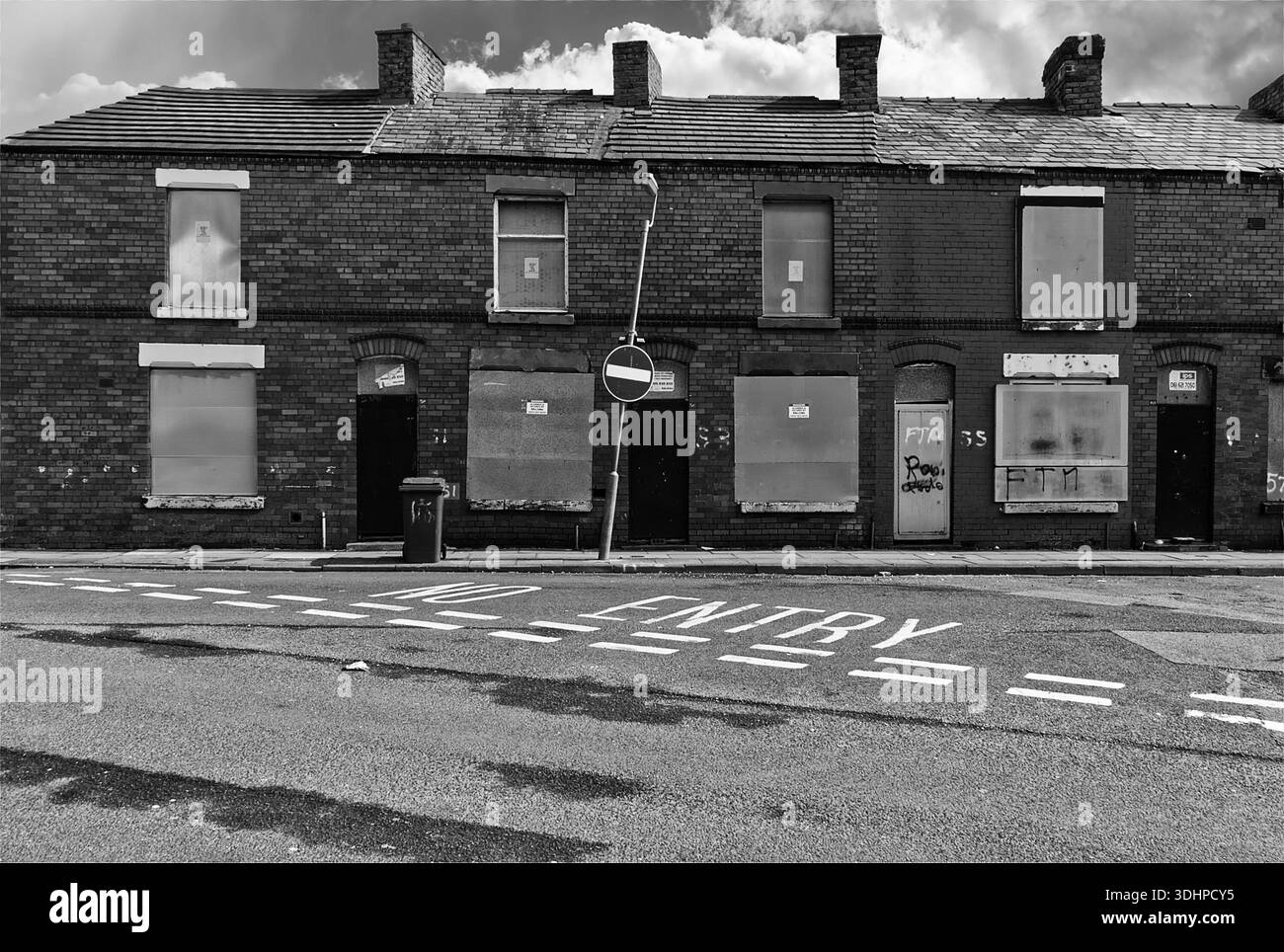 Rangée de maisons mitoyennes abandonnées à Liverpool, avec fenêtres scellées, graffitis, panneau d'interdiction d'entrée penché et signes de négligence à long terme. Banque D'Images