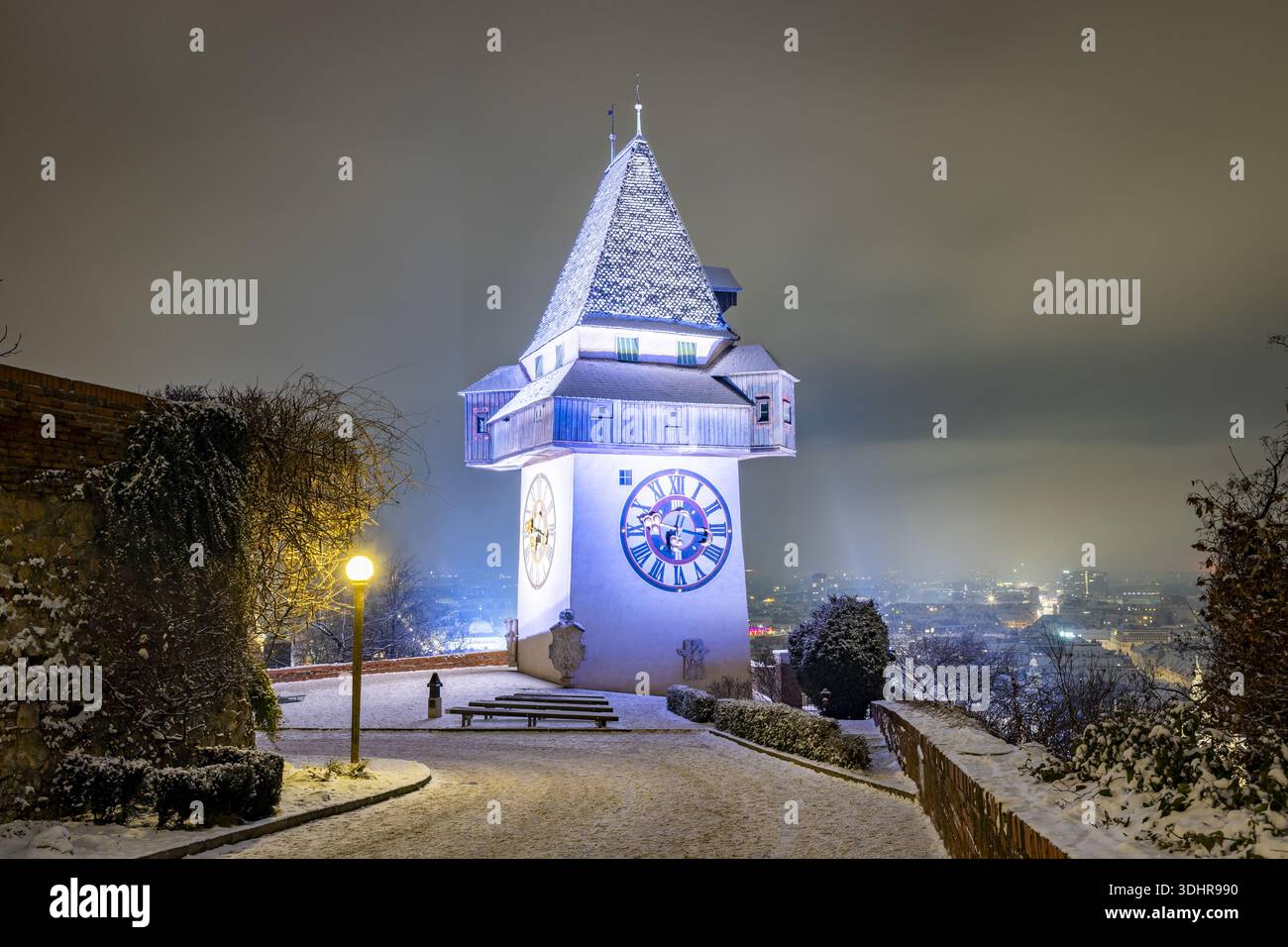 Vue de l'emblématique tour de l'horloge se dressant majestueusement au milieu d'un paysage enneigé, son visage illuminé projetant une lueur éthérée sur la scène calme, Graz, Banque D'Images