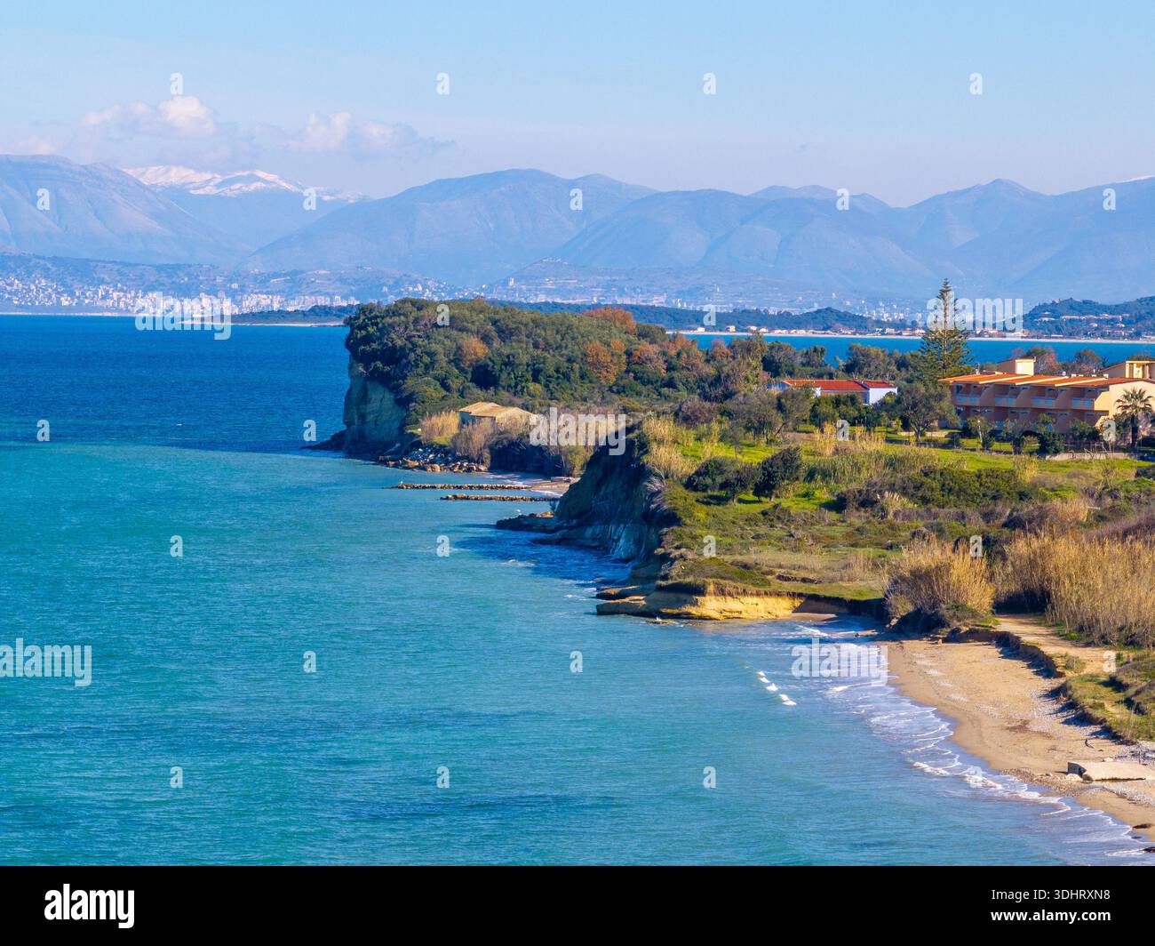 Paysage aérien de la côte de Corfou avec des montagnes enneigées massives en arrière-plan, falaises d'argile et mer Ionienne bleu profond, paysage printanier spectaculaire w Banque D'Images
