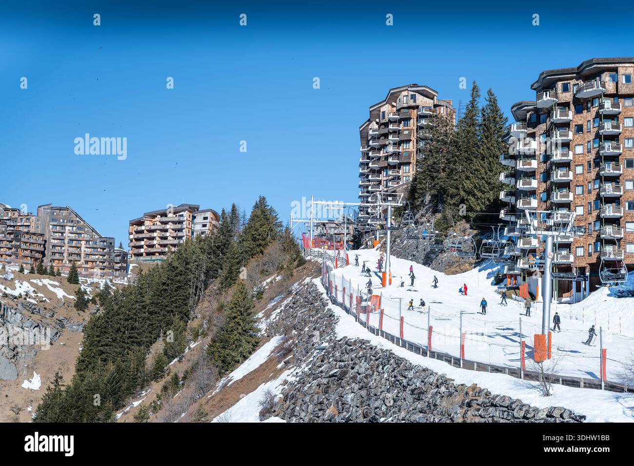Vue sur les remontées mécaniques transportant les skieurs sur une pente enneigée, entouré d'immeubles d'appartements en bois uniques, Avoriaz 1800, Auvergne-Rhône-Alpes, France. Banque D'Images
