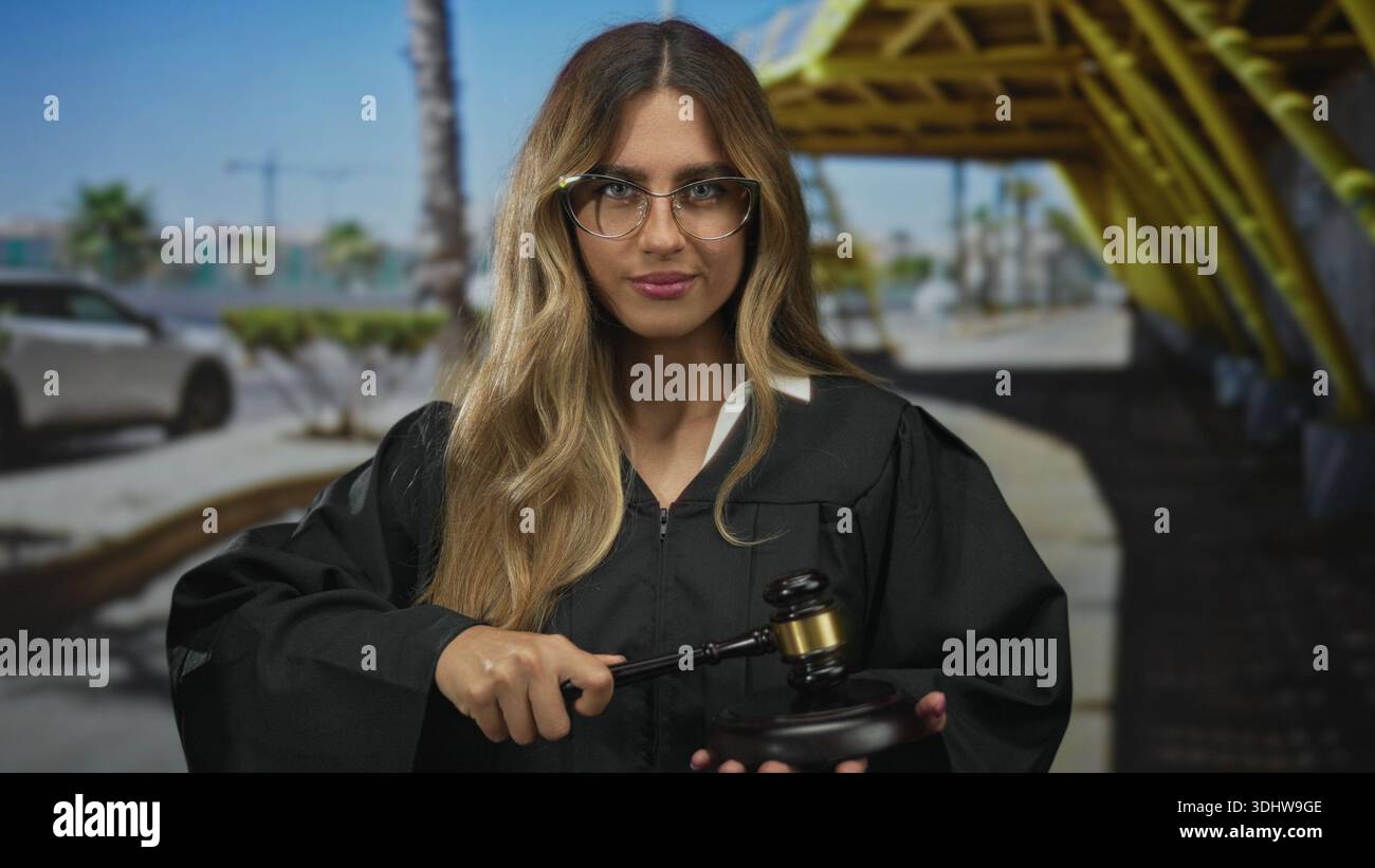 Une femme juge portant une robe frange un marteau en bois sur un bloc sonore dans la zone extérieure d'entrée du terminal de l'aéroport ; discipline d'équité de l'autorité judiciaire. Banque D'Images