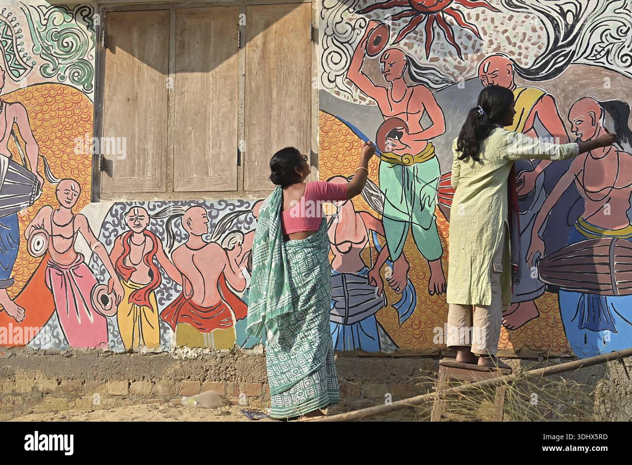 Agartala, Tripura, Inde, 12-01-2026 : des femmes peignent Alpona, sur le terrain avant le festival hindou Makar Sankranti dans le village de Lankamura à Agartala. Banque D'Images