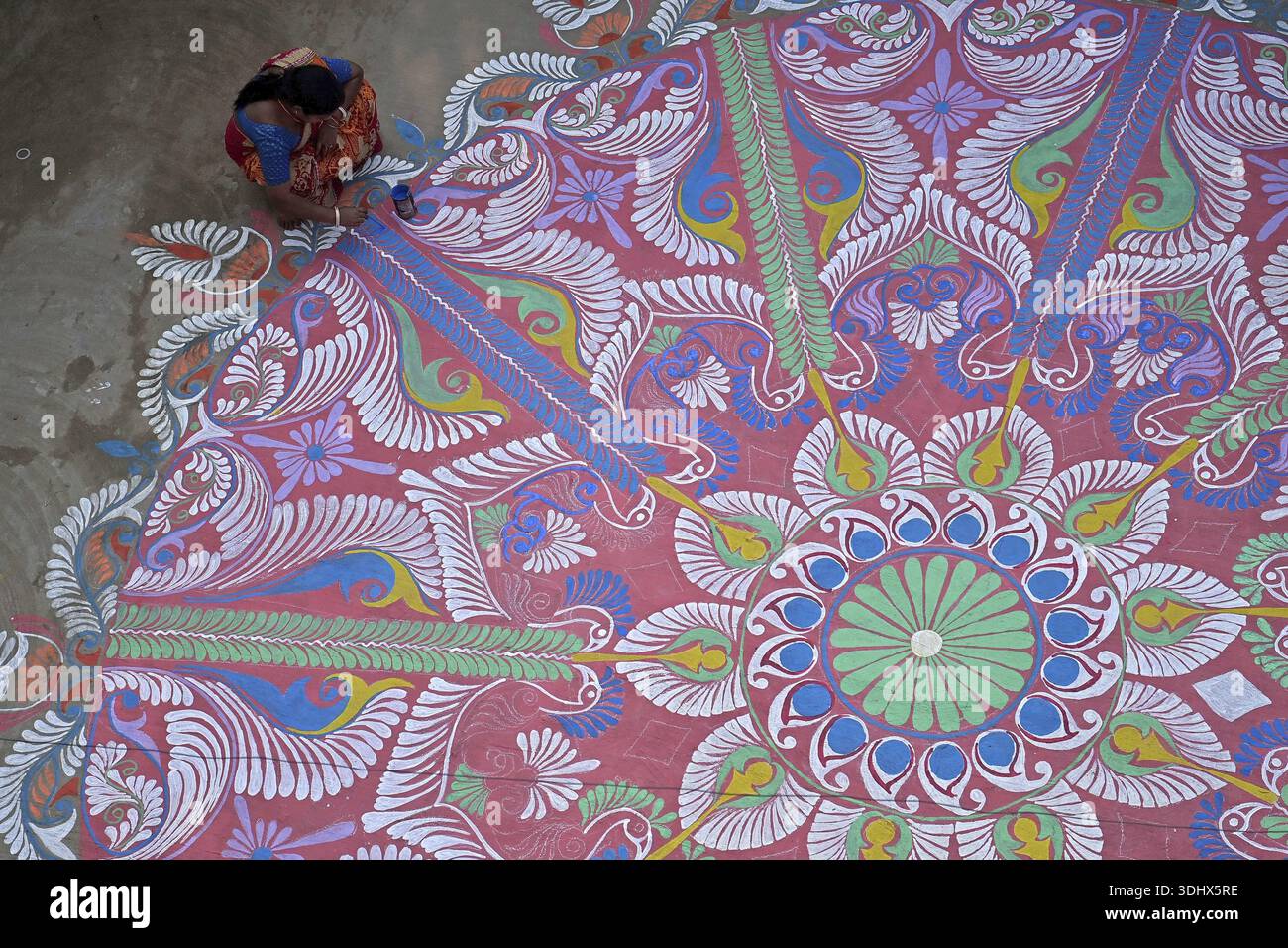 Agartala, Tripura, Inde, 12-01-2026 : des femmes peignent Alpona, sur le terrain avant le festival hindou Makar Sankranti dans le village de Lankamura à Agartala. Banque D'Images