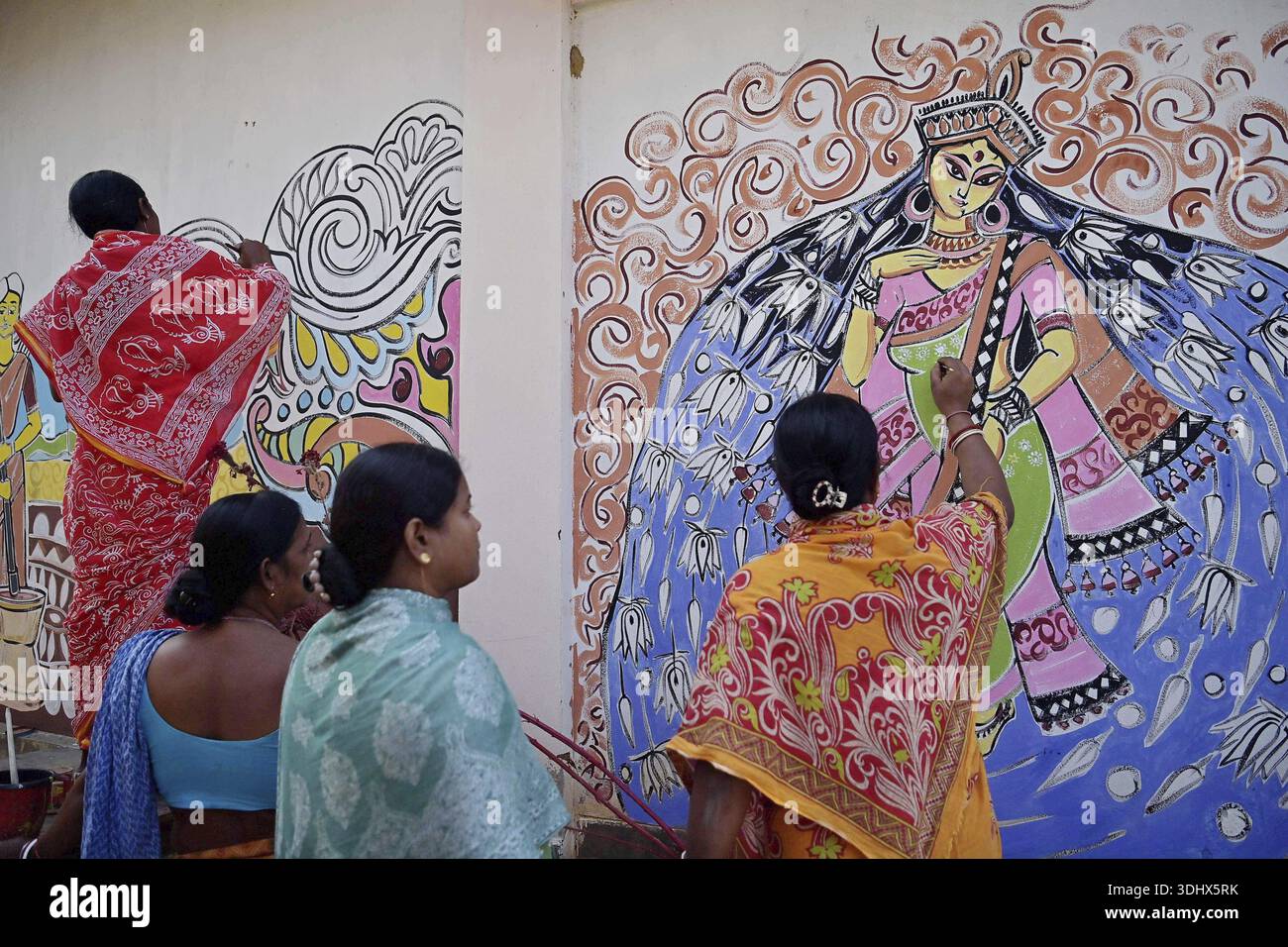 Agartala, Tripura, Inde, 12-01-2026 : des femmes peignent Alpona, sur le terrain avant le festival hindou Makar Sankranti dans le village de Lankamura à Agartala. Banque D'Images