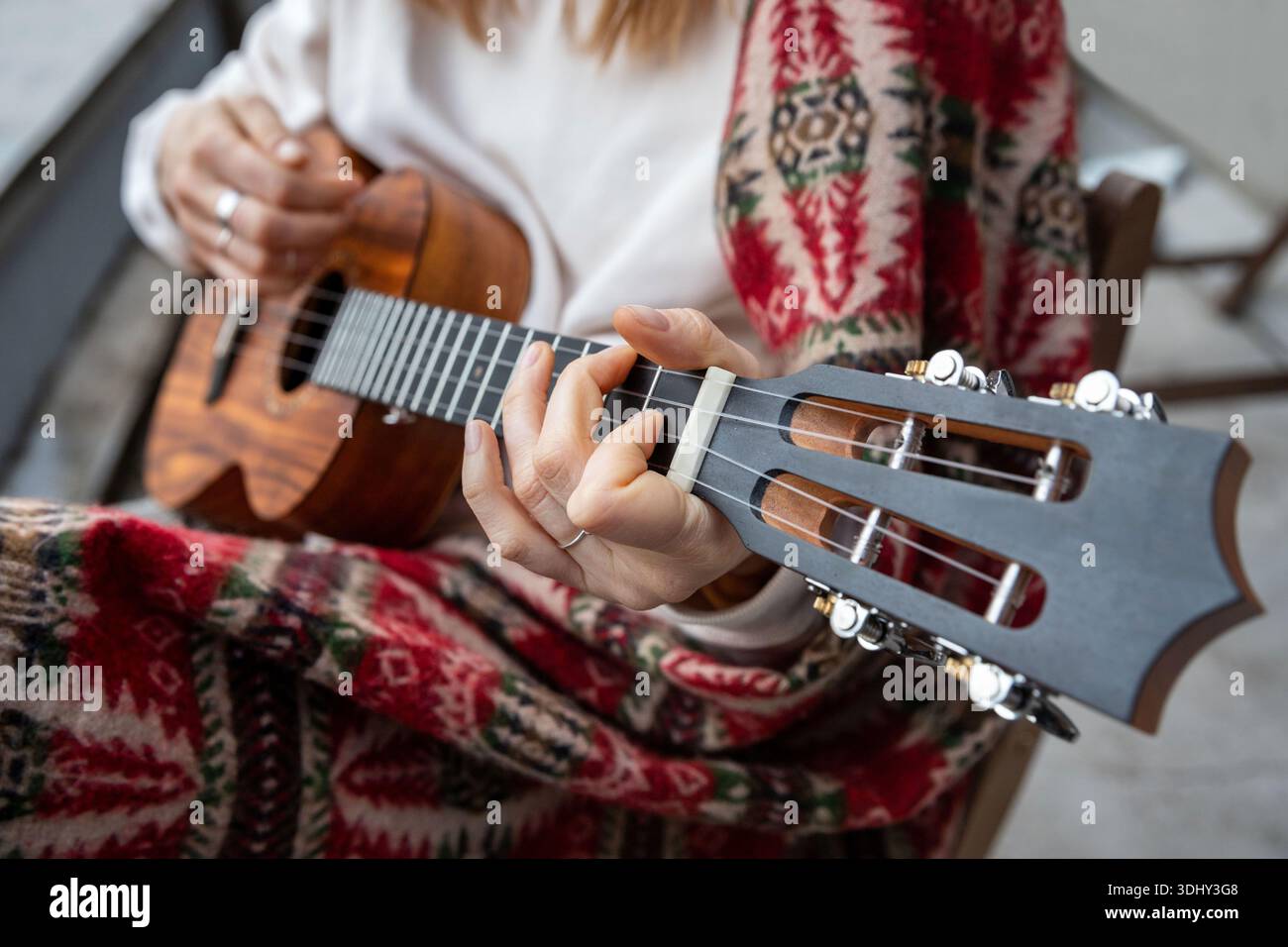 Femme jouant de la guitare hawaïenne, chante une chanson sur ukulélé vintage à la maison. Mise au point sélective. Gros plan... Banque D'Images
