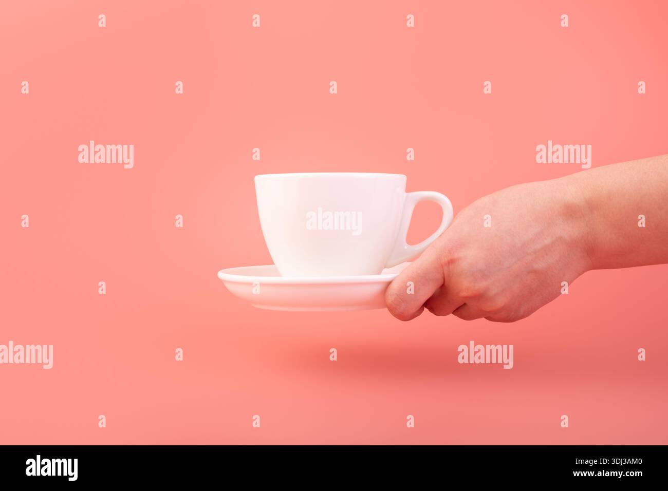 Thème du petit déjeuner et du café : main de la femme tenant une tasse de café en céramique blanche vide isolée sur un fond rose, publicité du café Banque D'Images