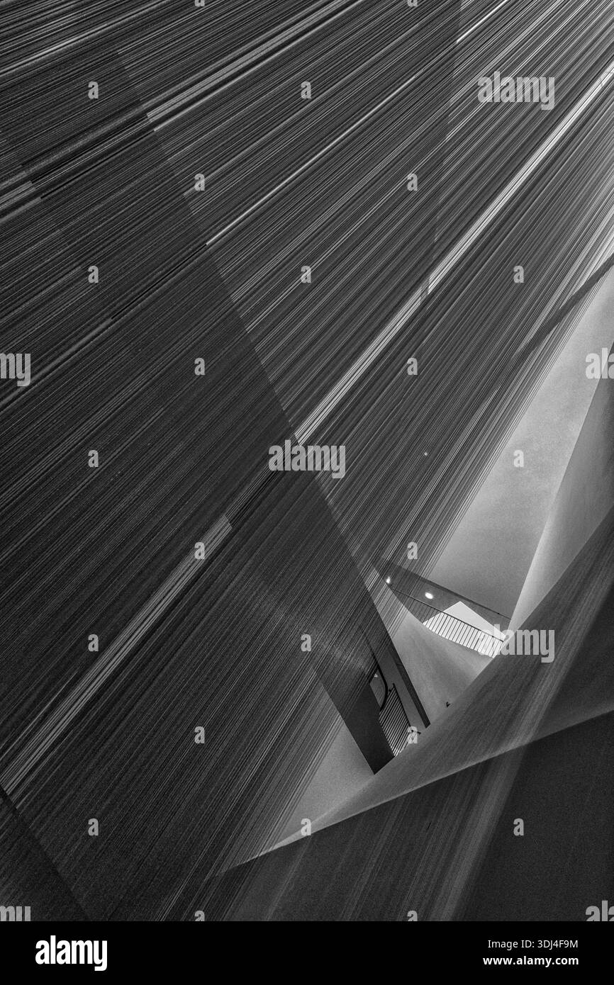 Intérieur architectural abstrait en monochrome avec des angles géométriques pointus et des installations de fils verticaux chatoyants. Banque D'Images