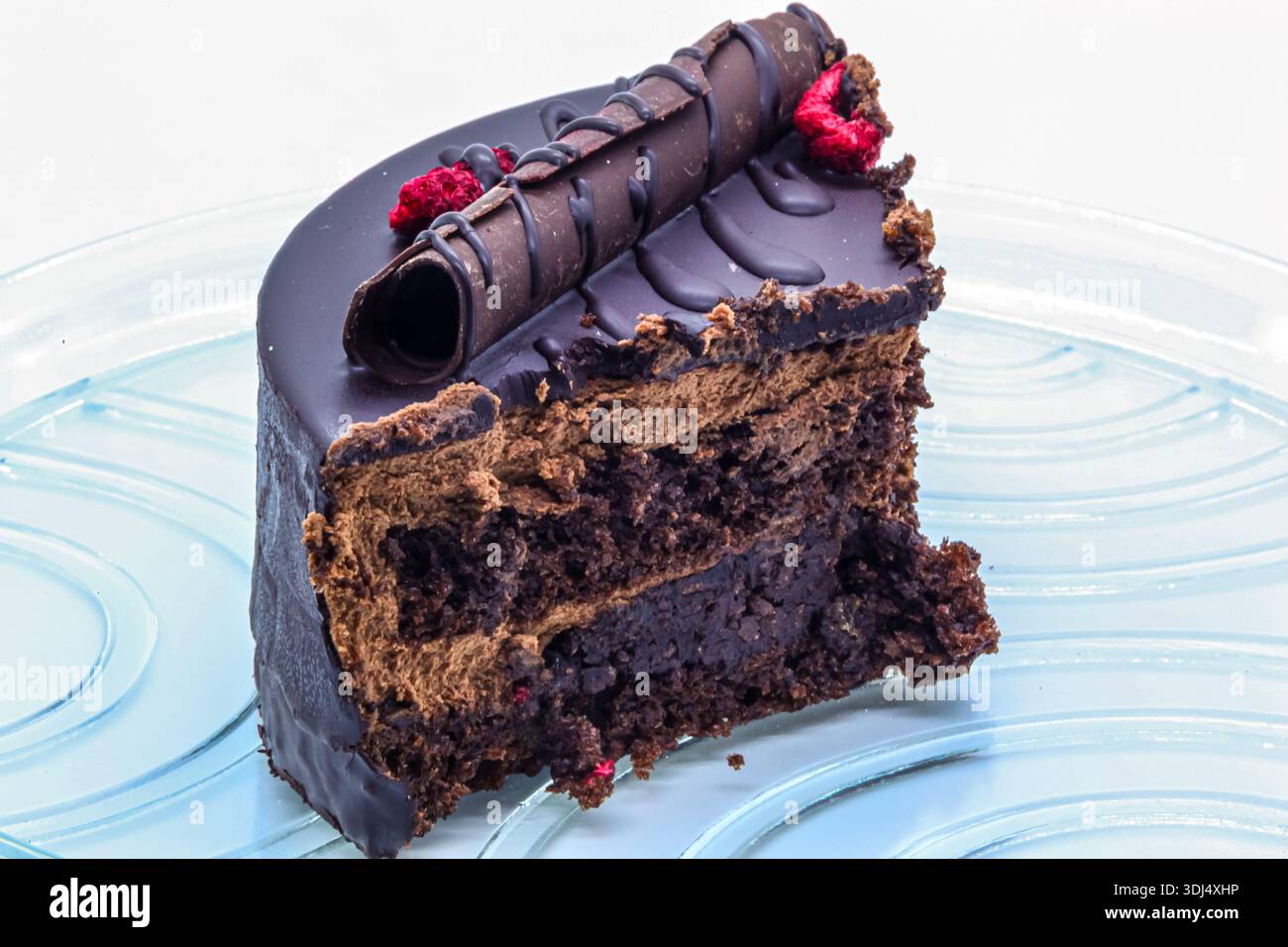 Dessert exquis avec glaçage au chocolat, décor et baies. Gros plan d'une tranche de gâteau montrant des couches délicates d'éponge et de crème. Banque D'Images
