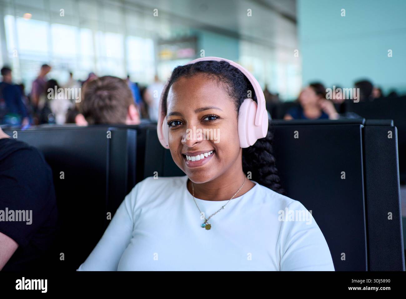 Femme souriante avec des écouteurs au salon de l'aéroport Banque D'Images