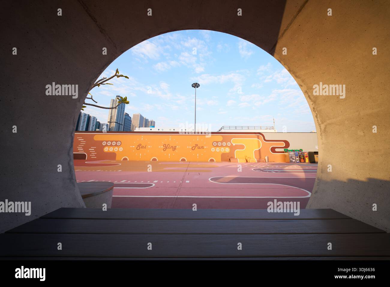 À l'intérieur du parc de SAI Ying Pun Harbourfront Park récemment rénové, la lumière chaude du matin filtre à travers une structure circulaire en forme de tuyau par derrière. Banque D'Images