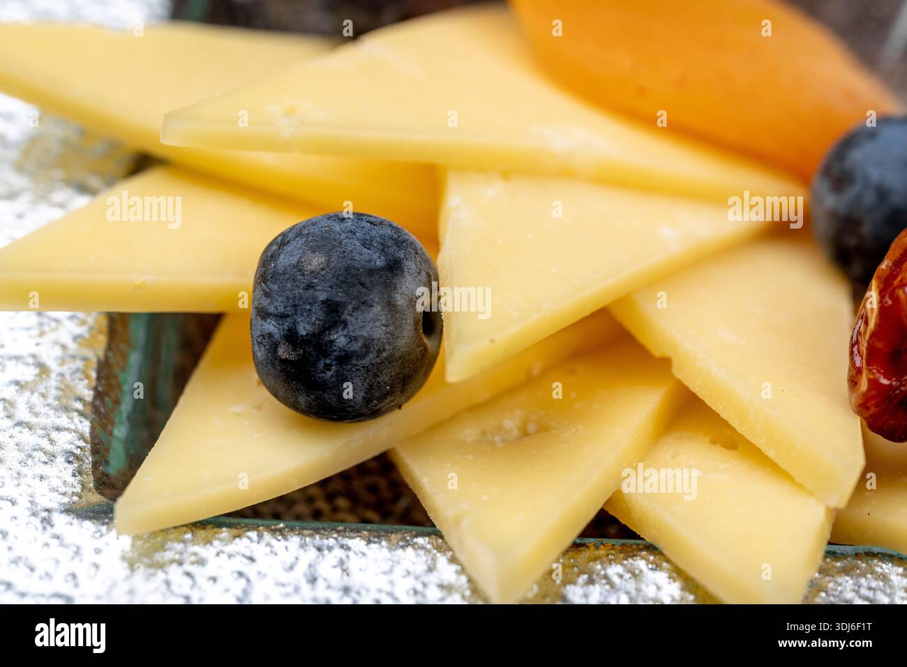 Gros plan d'un élégant hors-d'œuvre composé d'une variété de fromages à pâte dure et molle tranchés, accompagnés de myrtilles, de fruits physalis, de bière rouge séchée Banque D'Images