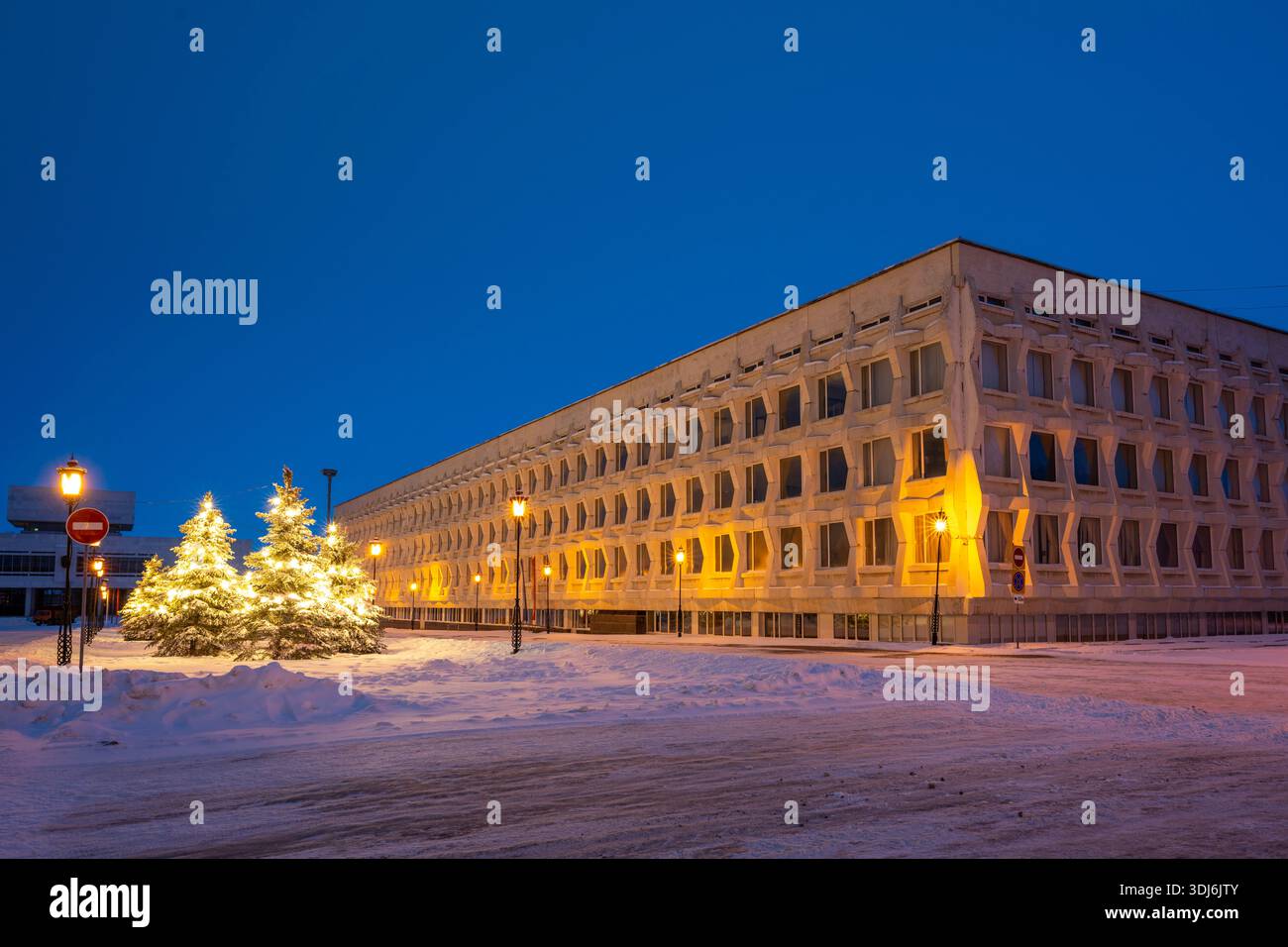 Oulianovsk, Russie - 14 février 2022 : arbres de Noël enneigés décorés de guirlandes, de lampadaires et de l'Université pédagogique d'État d'Oulianovsk. Banque D'Images