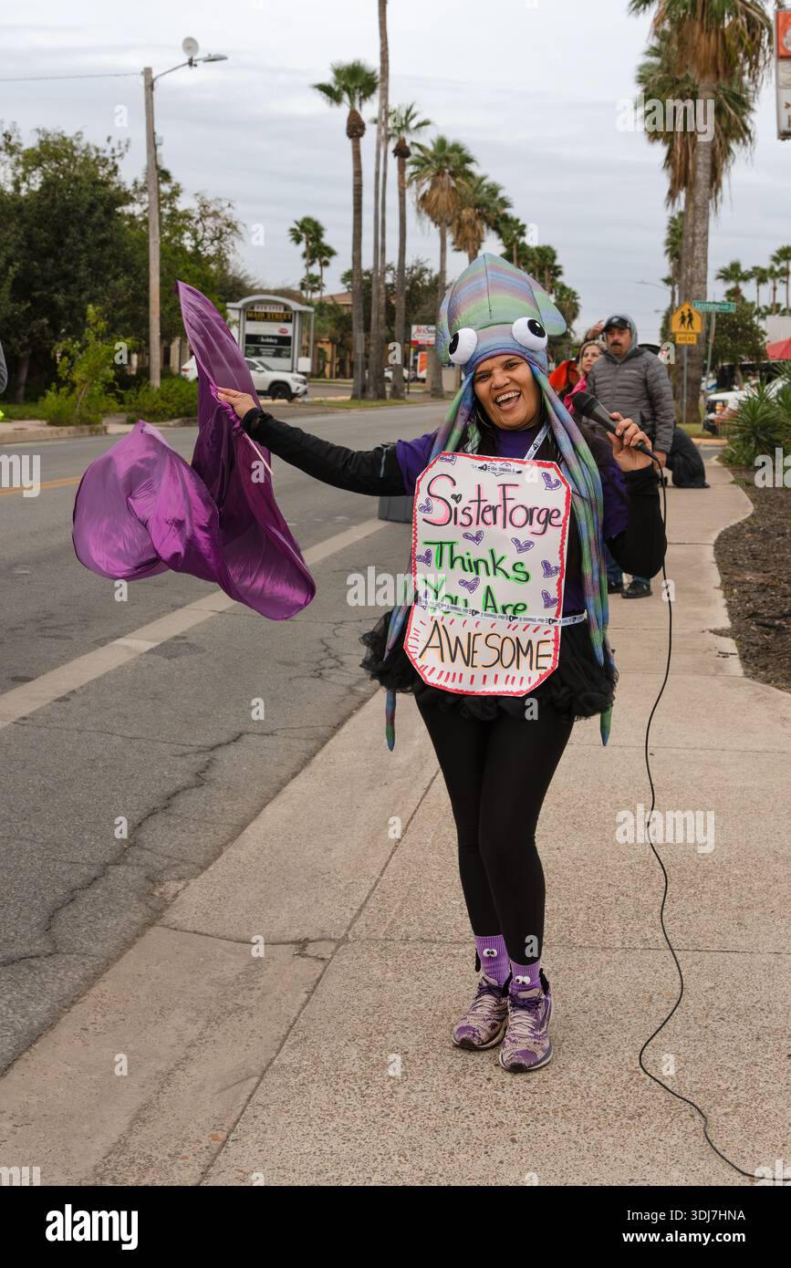 Un supporter de course féminin agitant un drapeau violet vif se tient sur la touche du McAllen Marathon, McAllen, Texas, États-Unis. POUR USAGE ÉDITORIAL UNIQUEMENT. Banque D'Images