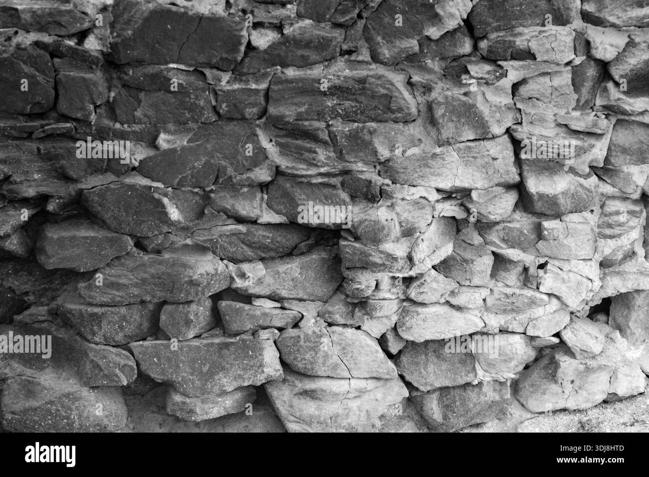 Mur de maçonnerie en gravats rustiques avec des pierres irrégulières et grossières de différentes tailles, liées par du mortier visible, créant une surface texturée et vieillie. Banque D'Images