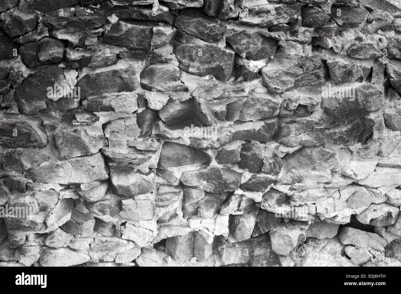 Mur de maçonnerie en gravats rustiques avec des pierres irrégulières et grossières de différentes tailles, liées par du mortier visible, créant une surface texturée et vieillie. Banque D'Images