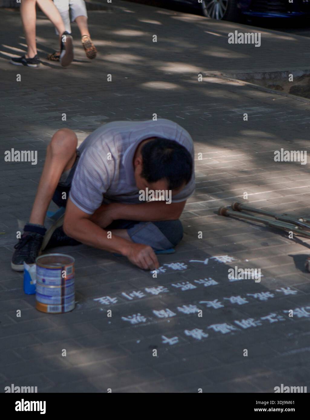 Un homme handicapé écrivant en chinois avec de la craie sur le sol d'une rue à Pékin. Chine 2016 Banque D'Images