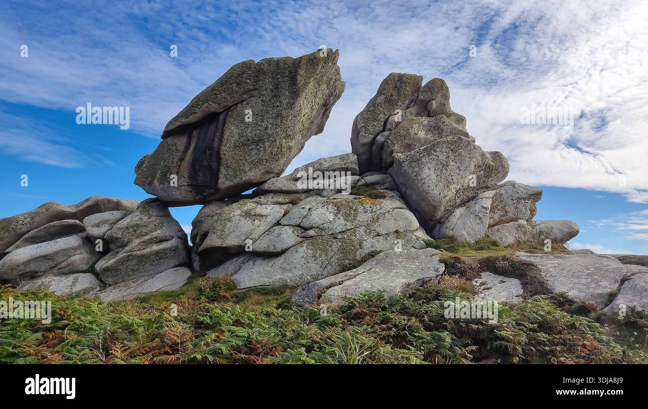 Formations rocheuses massives sous un ciel bleu avec des nuages, entourées de plantes. Banque D'Images