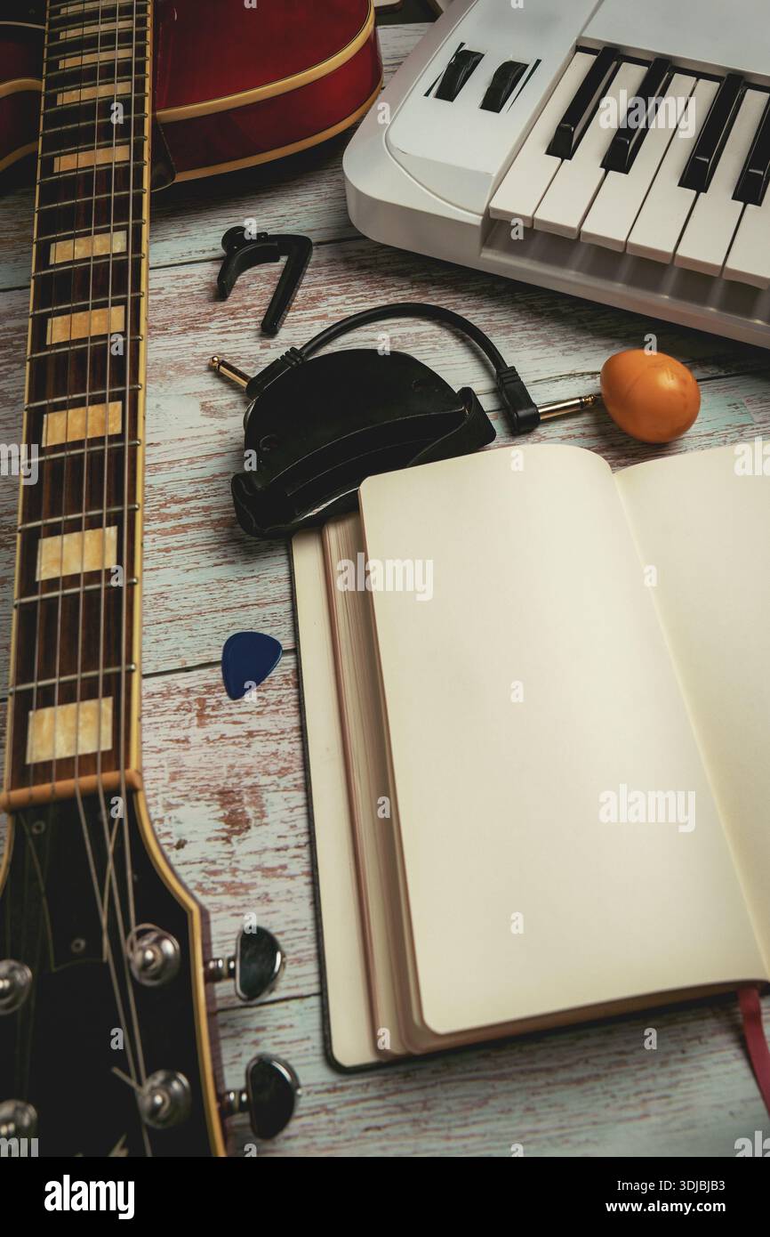 Vue de dessus plat de l'espace de travail d'enregistrement à la maison avec guitare, clavier, microphone et cahier vierge sur fond en bois. Production musicale et songwrit Banque D'Images