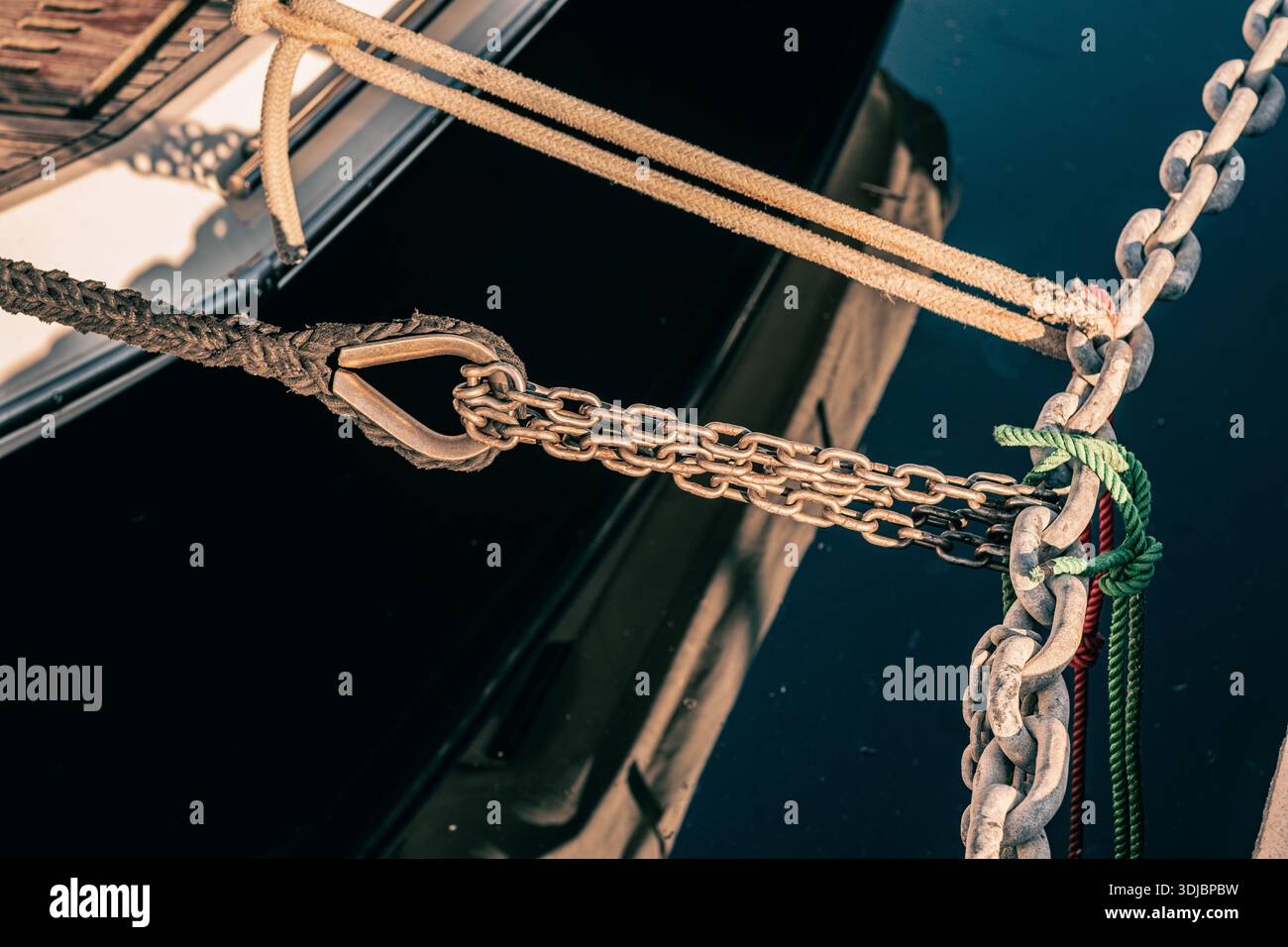 Les chaînes et les cordes sont attachées à des anneaux métalliques encastrés dans le remblai de béton d'une marina. Chaînes d'amarrage, cordes, nœuds et amortisseurs pour l'amarrage Banque D'Images