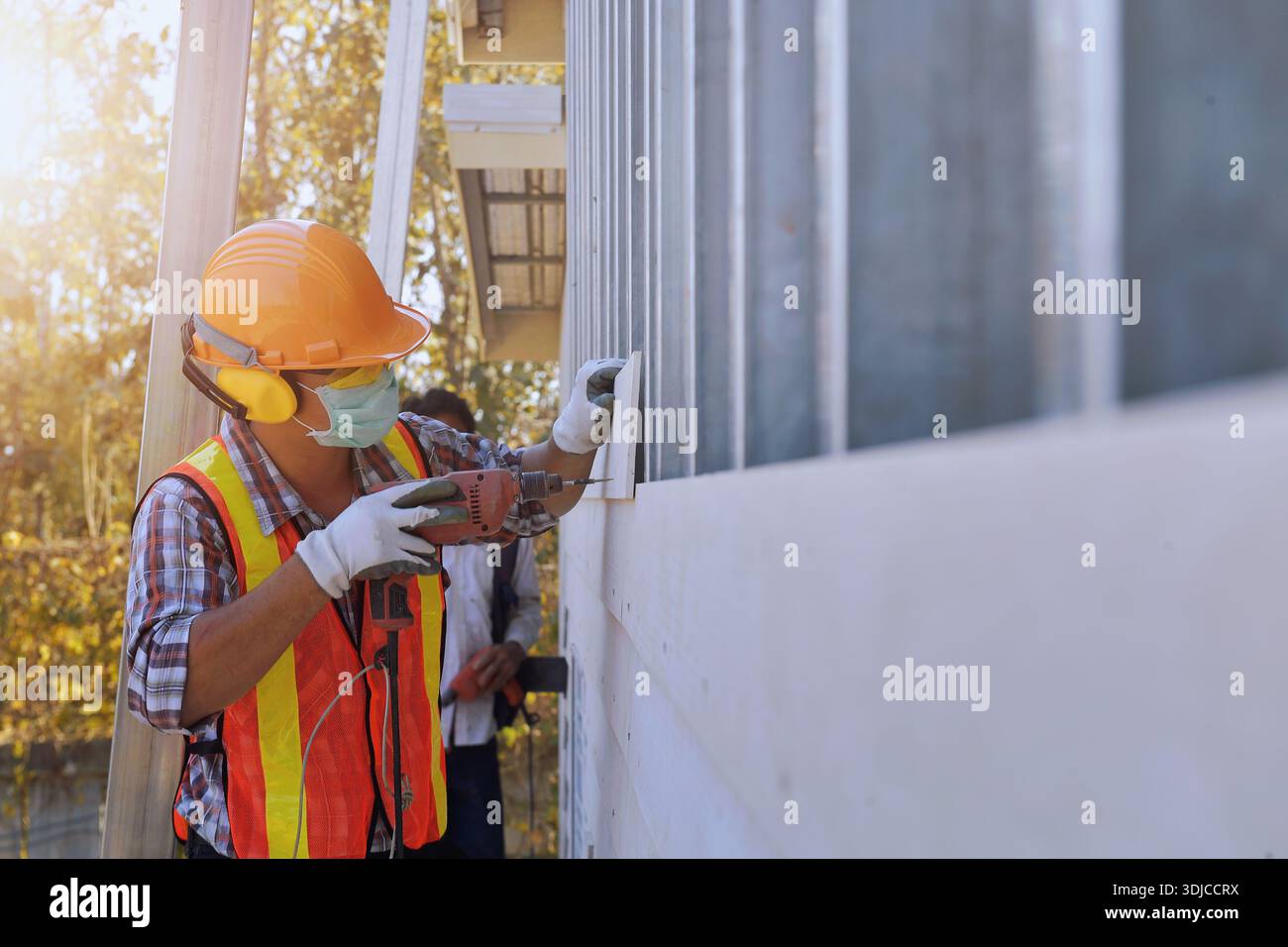 Vue latérale rapprochée d'un travailleur de la construction portant des vêtements de travail de protection et un masque facial travaillant sur un bâtiment, Thaïlande Banque D'Images