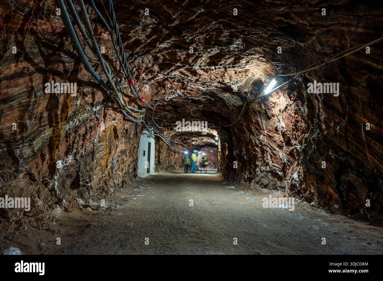 Tunnel souterrain de mine de sel rocheux à Loulé, Algarve, avec des murs minéraux robustes, un éclairage industriel et des câbles aériens mettant en valeur l'exploitation minière en terre profonde. Banque D'Images