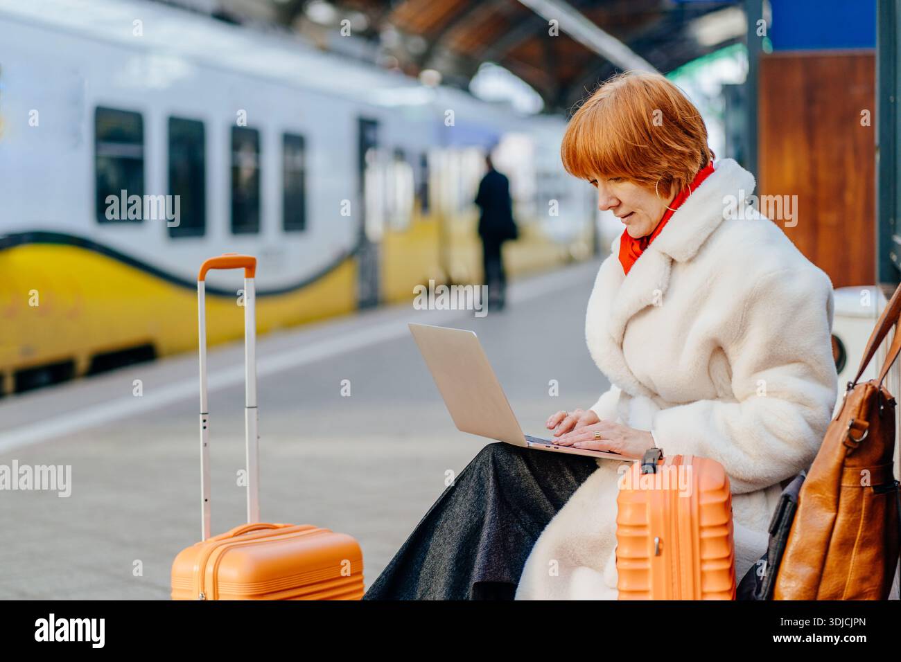 Femme rousse caucasienne freelance travaillant sur ordinateur portable à la plate-forme de la gare Banque D'Images