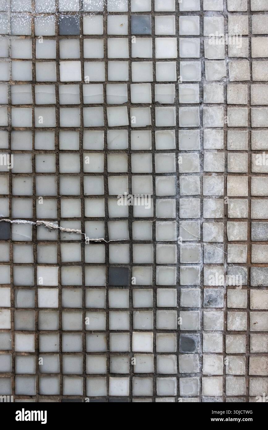Gros plan de petites mosaïques carrées avec coulis usé et variations de couleurs subtiles formant un motif de grille géométrique Banque D'Images