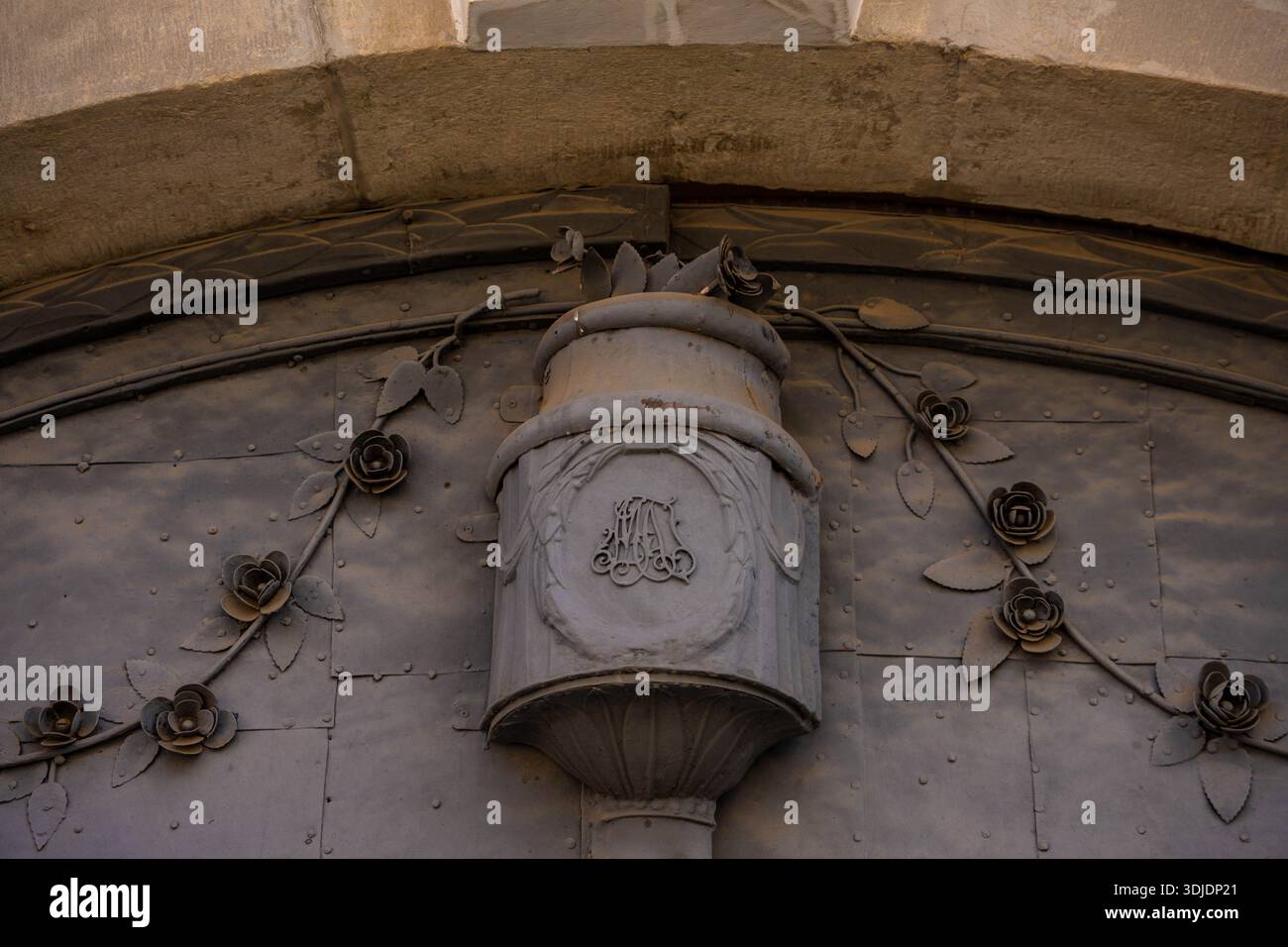 Gros plan détaillé d'une porte en métal gris foncé sur un bâtiment historique. L'image présente un relief ornemental surélevé en forme de vaisseau avec un mono Banque D'Images