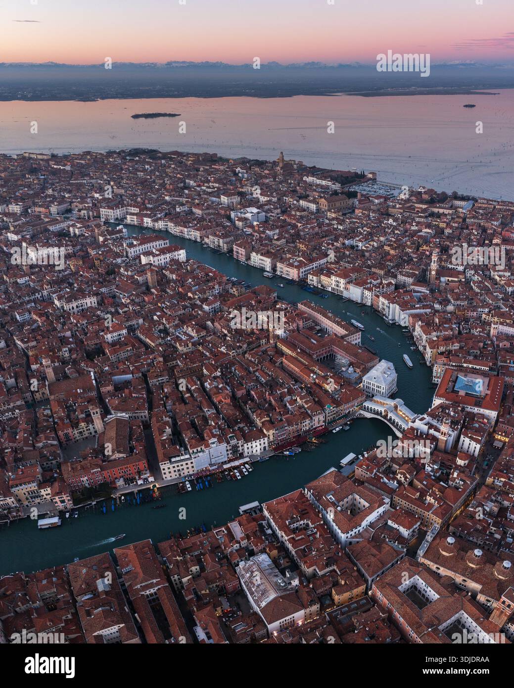 Vue aérienne des toits en terre cuite en cascade vers le Grand canal sinueux, ponctué de ponts emblématiques, Venise, Vénétie, Italie. Banque D'Images