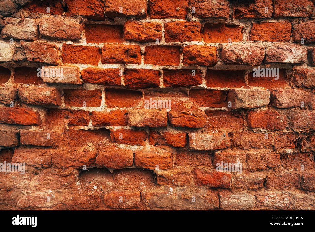 Texture d'un mur de briques rouges vieillies avec des joints de mortier blanc fortement érodés, des briques exposées et des détails de surface rugueux altérés par les intempéries pour la décomposition urbaine et l'arc Banque D'Images