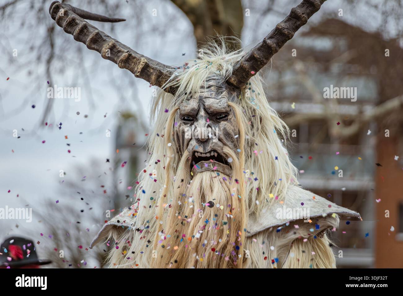 Zug, Suisse - 1er mars 2025 : une personne en costume de bête à fourrure Tschaggatta avec un masque en bois à cornes lors d'un défilé Fasnacht du carnaval d'hiver suisse Banque D'Images