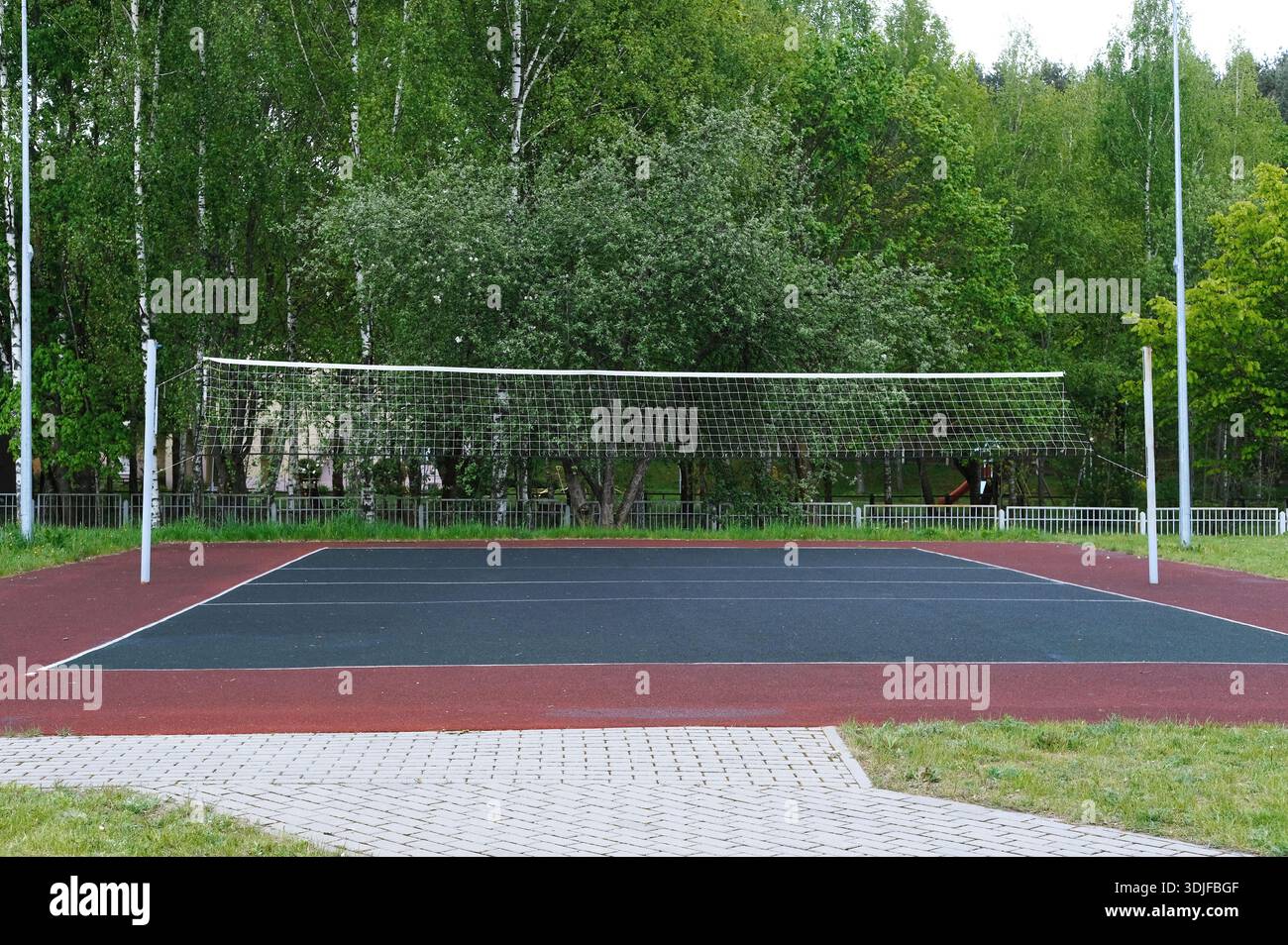 Terrain de volley-ball avec filet, situé dans un environnement vert, idéal pour le personnel militaire et les étudiants, encourageant le travail d'équipe et l'activité physique dans un na Banque D'Images